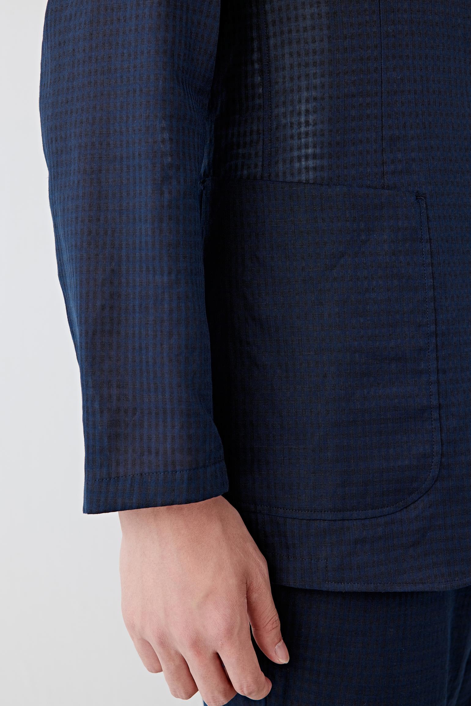 Close-up of the sleeve and fabric texture showing the lightweight weave, soft hand and subtle tonal variation characteristic of the checked linen and cotton fabric.