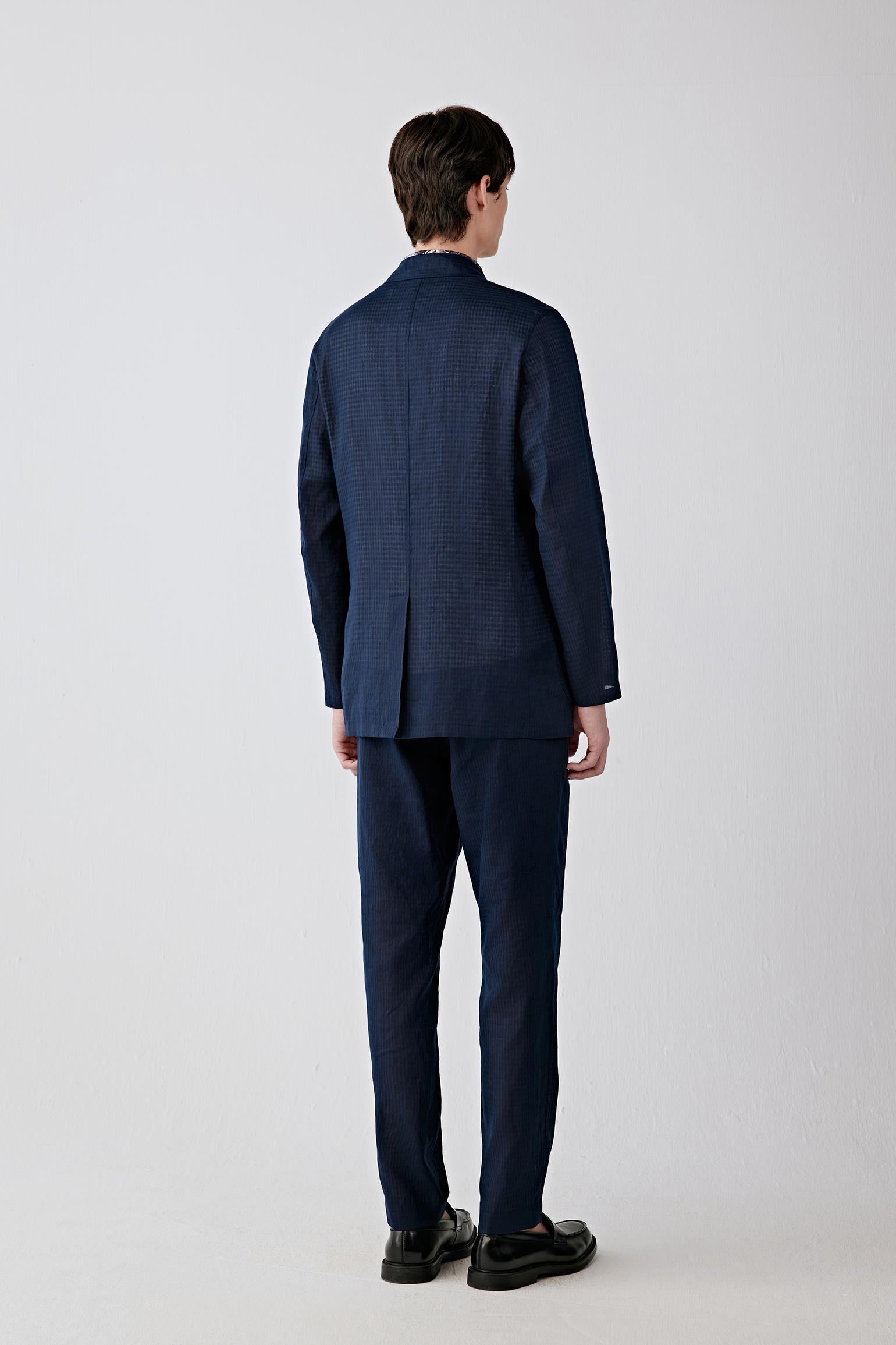 Back view emphasizing the clean proportions and lightly structured silhouette. The subtle black check pattern introduces tonal depth while maintaining an understated appearance.