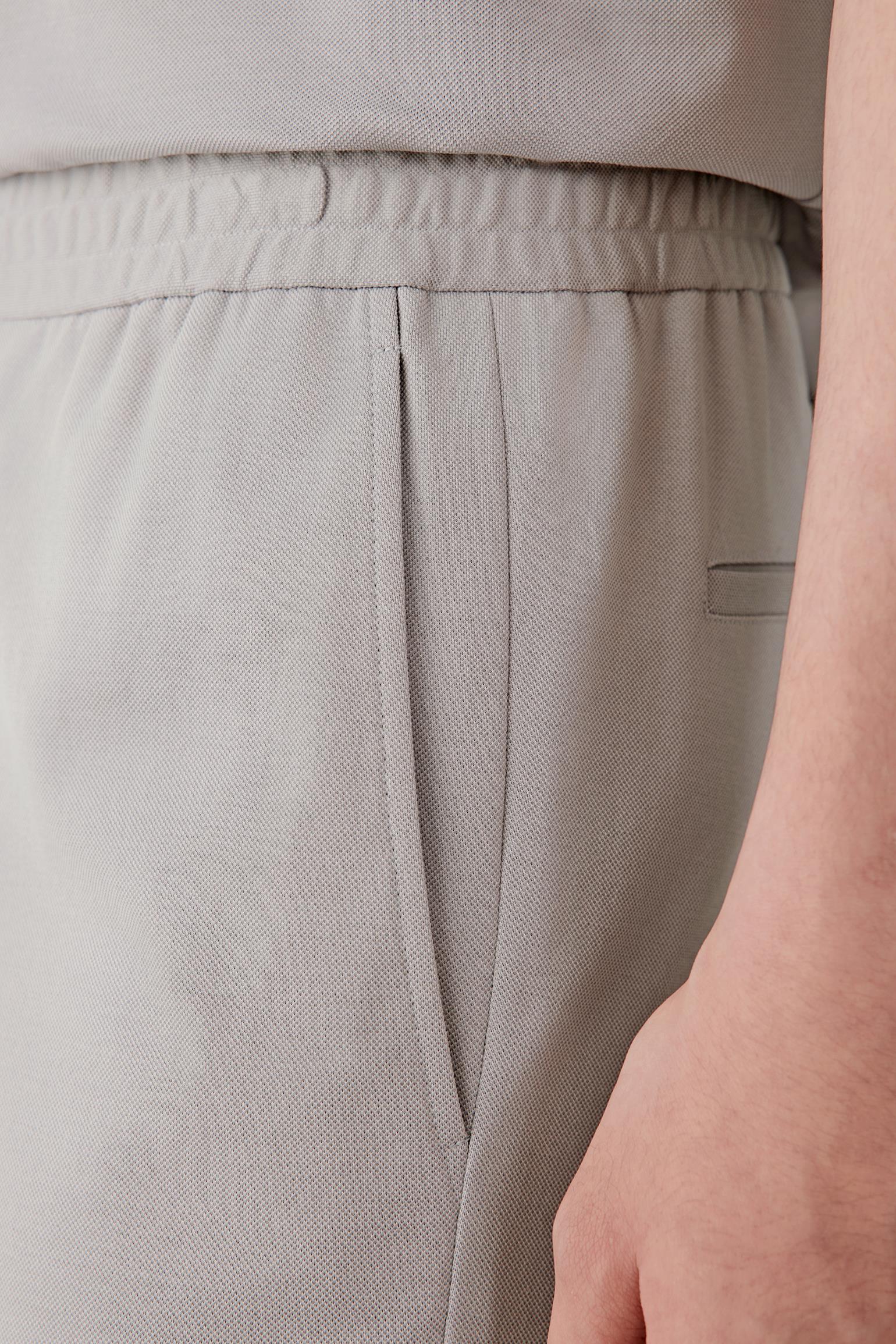 Close-up of the fabric and pocket construction showing the lightly textured piqué surface, clean stitching and soft matte finish of the jersey material.
