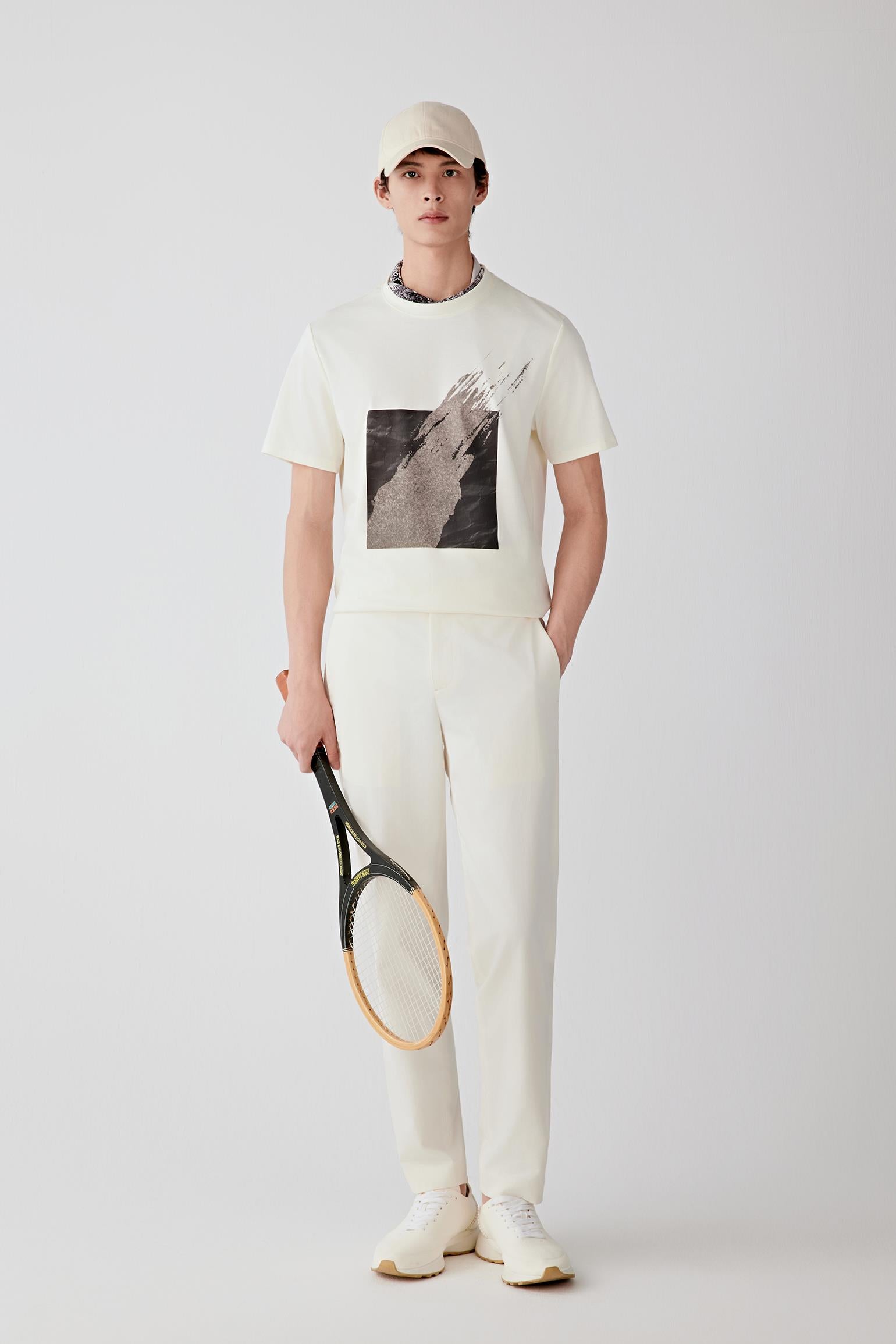 Front view of a man wearing a cream T-shirt in cotton interlock, highlighting the relaxed silhouette, smooth surface and dense knit construction. The printed artwork at the front contrasts with the clean appearance of the interlock fabric.