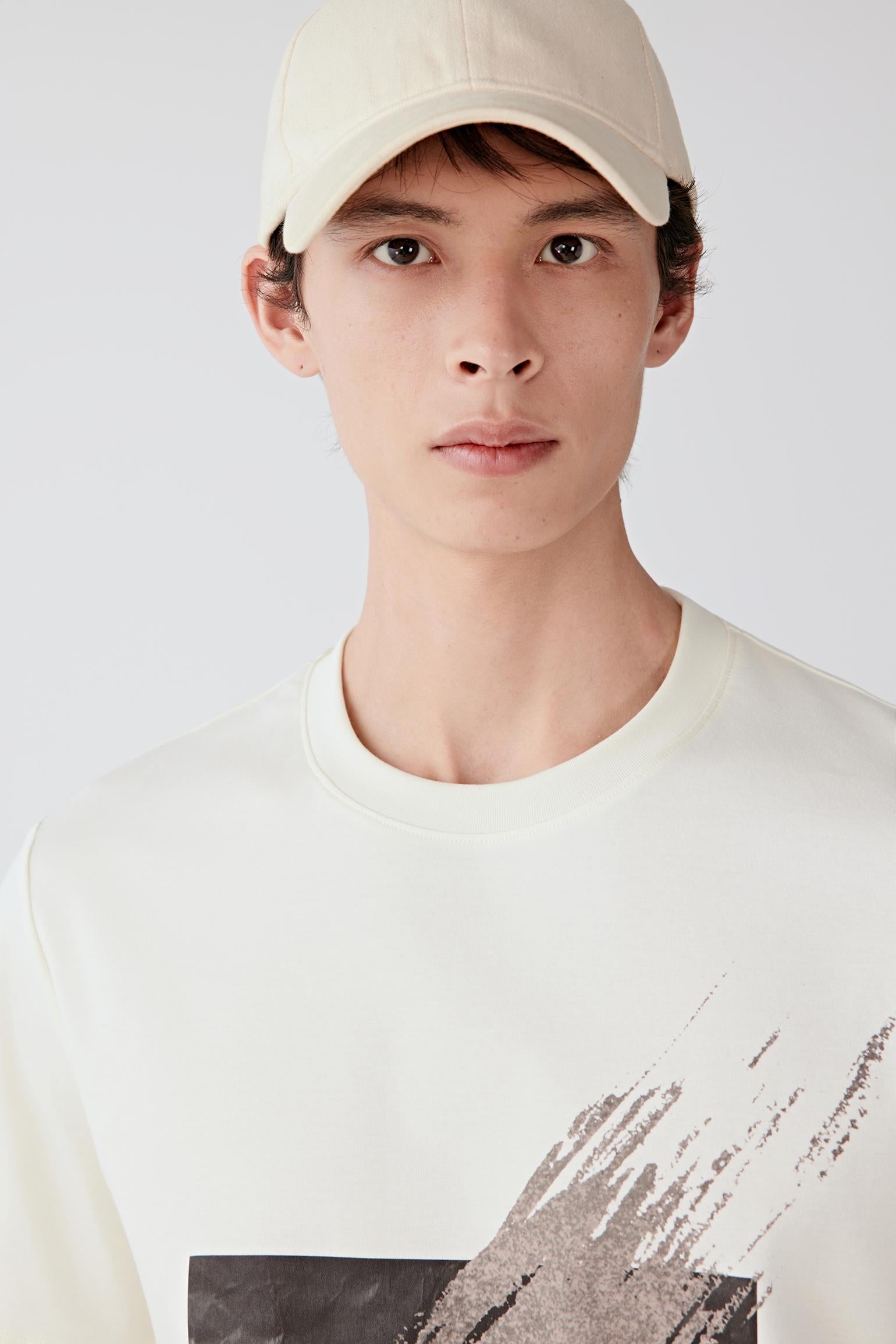 Close-up portrait focusing on the crew neckline, upper body construction and printed front motif. The image reveals the smooth texture, compact knit surface and clean finishing details.