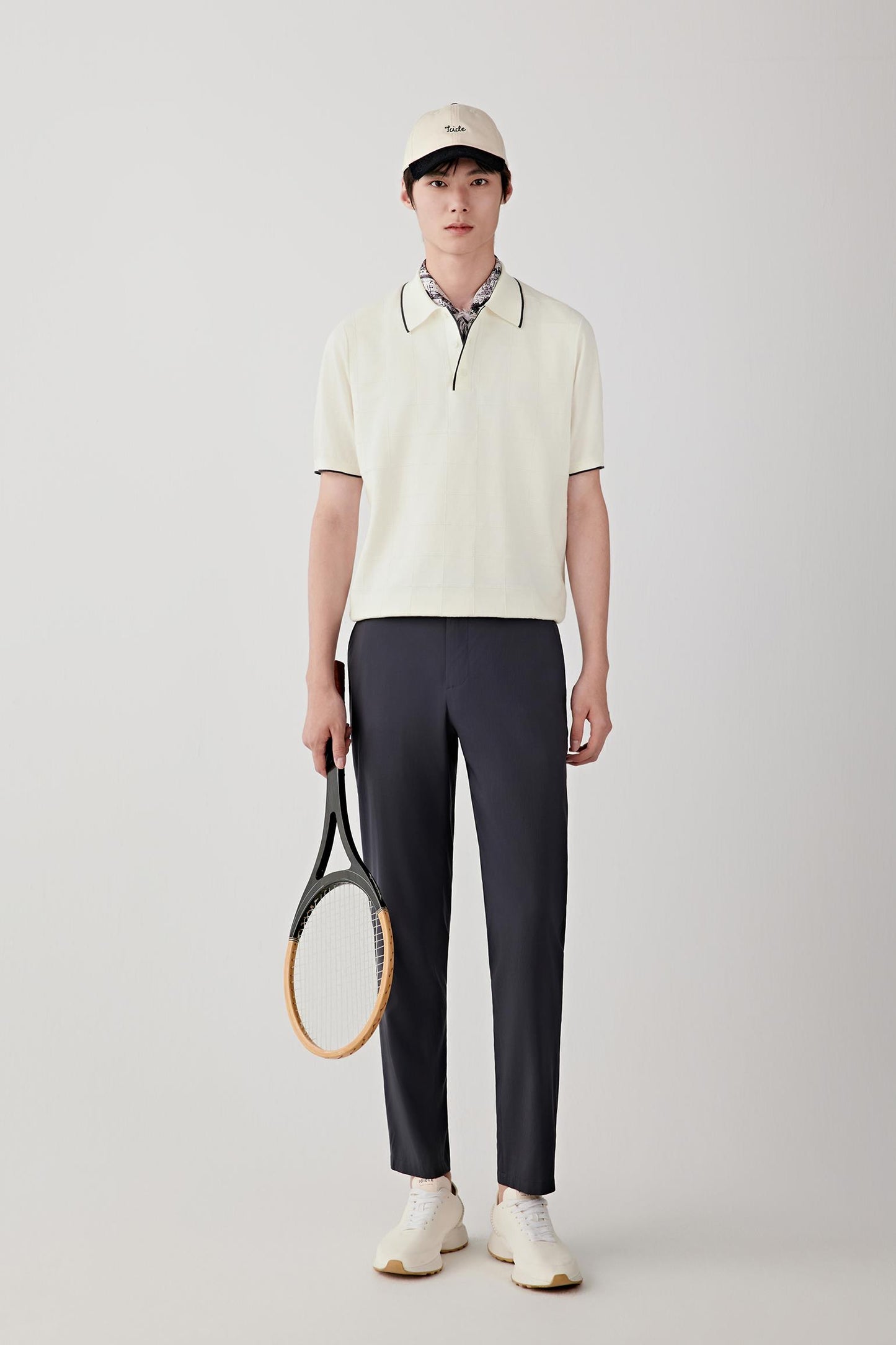 Front view of a man wearing an ivory polo shirt in cotton yarn, highlighting the relaxed silhouette, lightweight knit construction and clean appearance. The subtle texture of the knit creates gentle depth across the surface while maintaining an even finish.