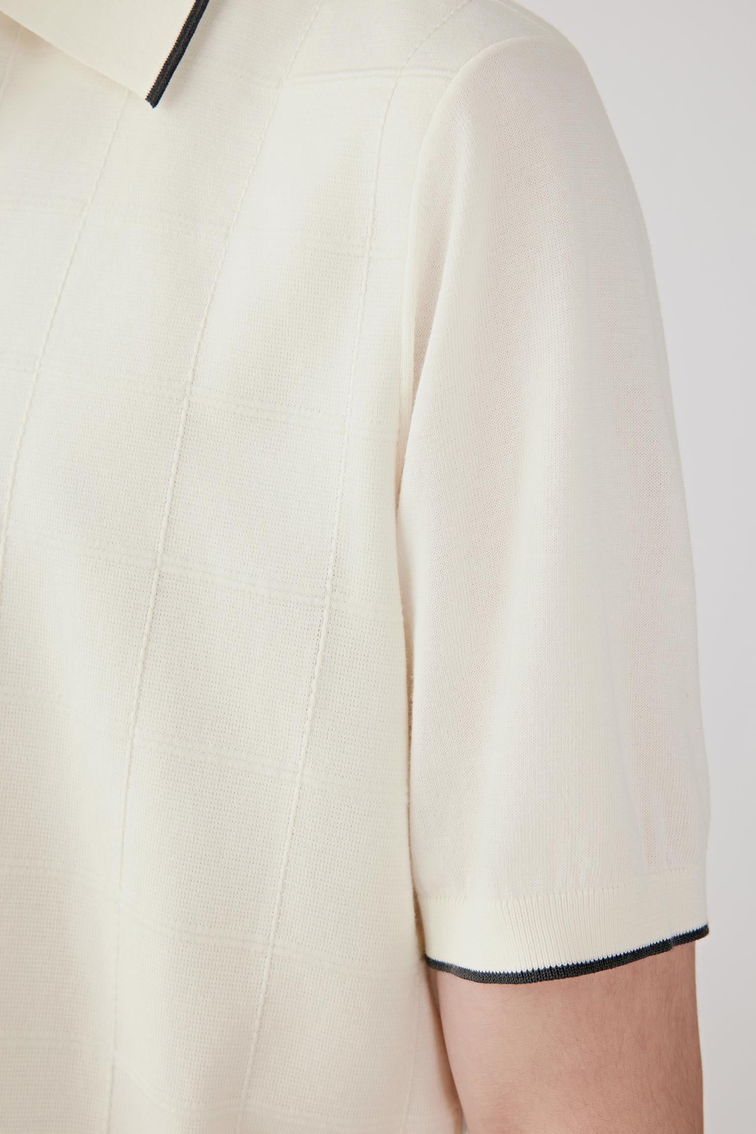Close-up of the sleeve showing the contrasting trim at the cuff, the smooth knit surface and the lightweight structure of the cotton yarn. The image highlights the precise finishing and understated texture of the fabric.