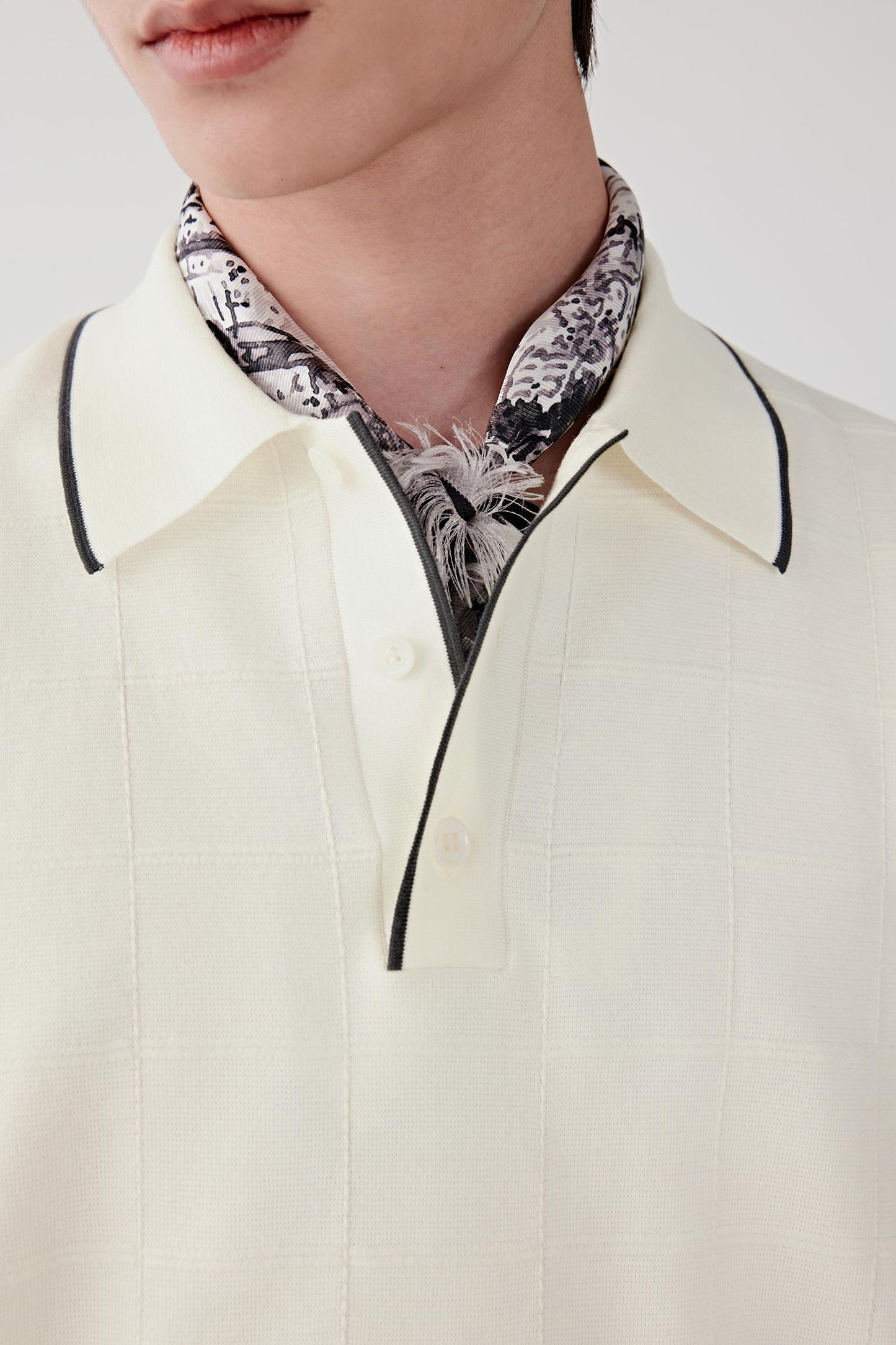Close-up focusing on the polo-style neckline and contrasting trim at the collar. The image reveals the fine knit texture, clean finishing and subtle detailing that defines the upper construction.