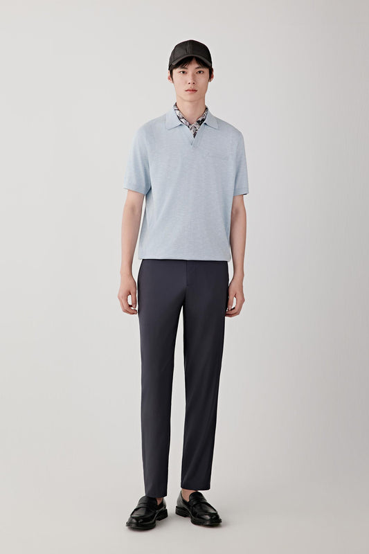 Full-length view showing the polo shirt paired with tailored trousers. The image emphasizes the clean proportions, fluid drape and lightweight structure of the knit while illustrating the garment's relaxed yet refined appearance.