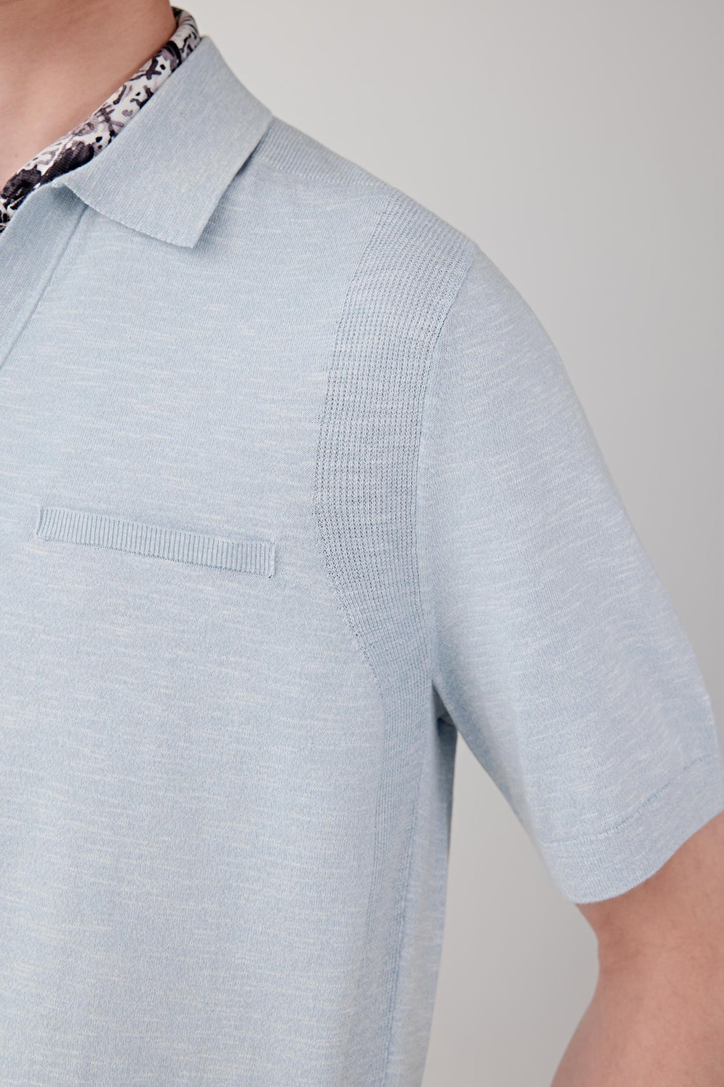 Close-up of the sleeve and shoulder area showing the lightweight knit structure, fine slub irregularities and smooth drape of the fabric. The image emphasizes the balance between texture and softness.