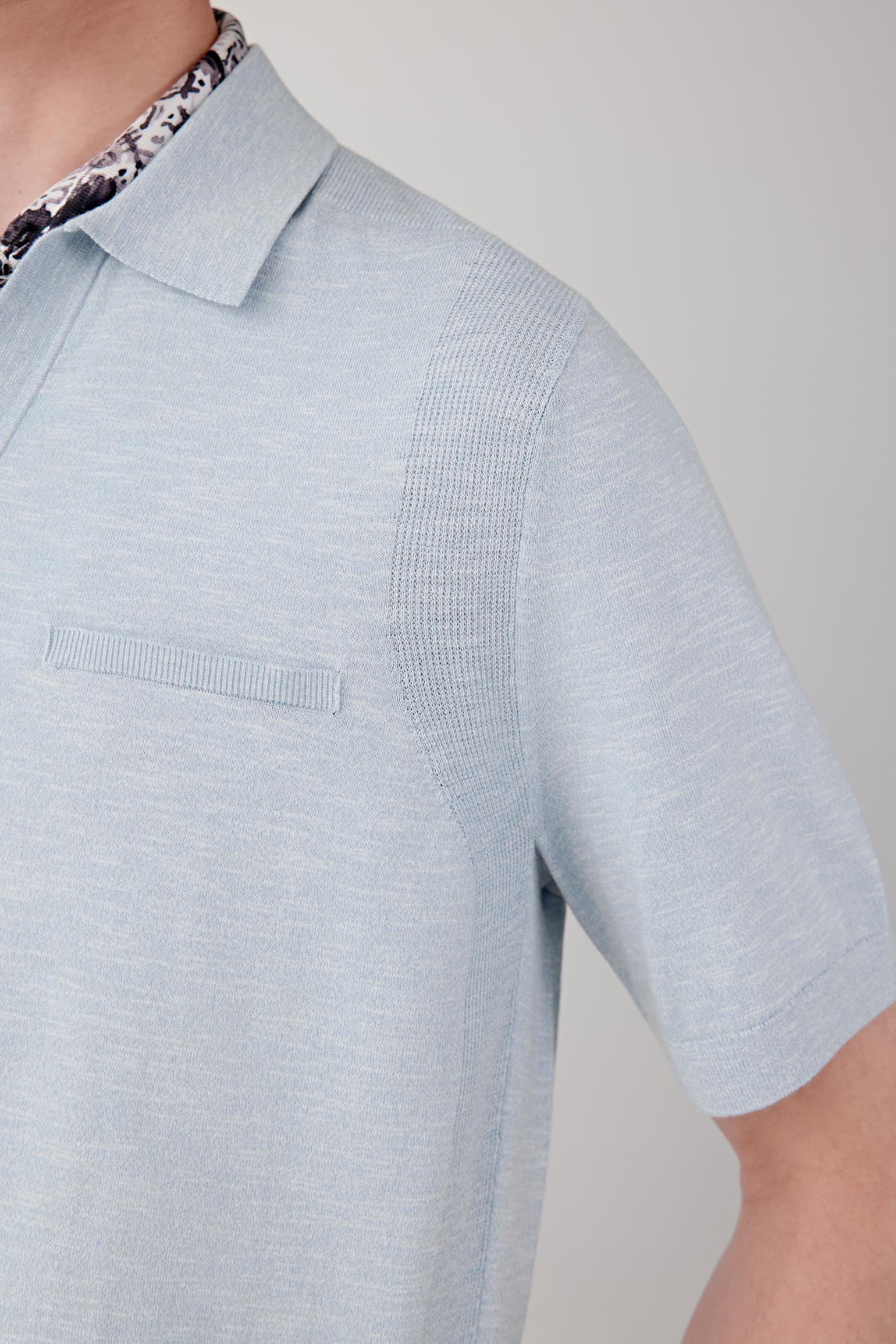Close-up of the sleeve and shoulder area showing the lightweight knit structure, fine slub irregularities and smooth drape of the fabric. The image emphasizes the balance between texture and softness.