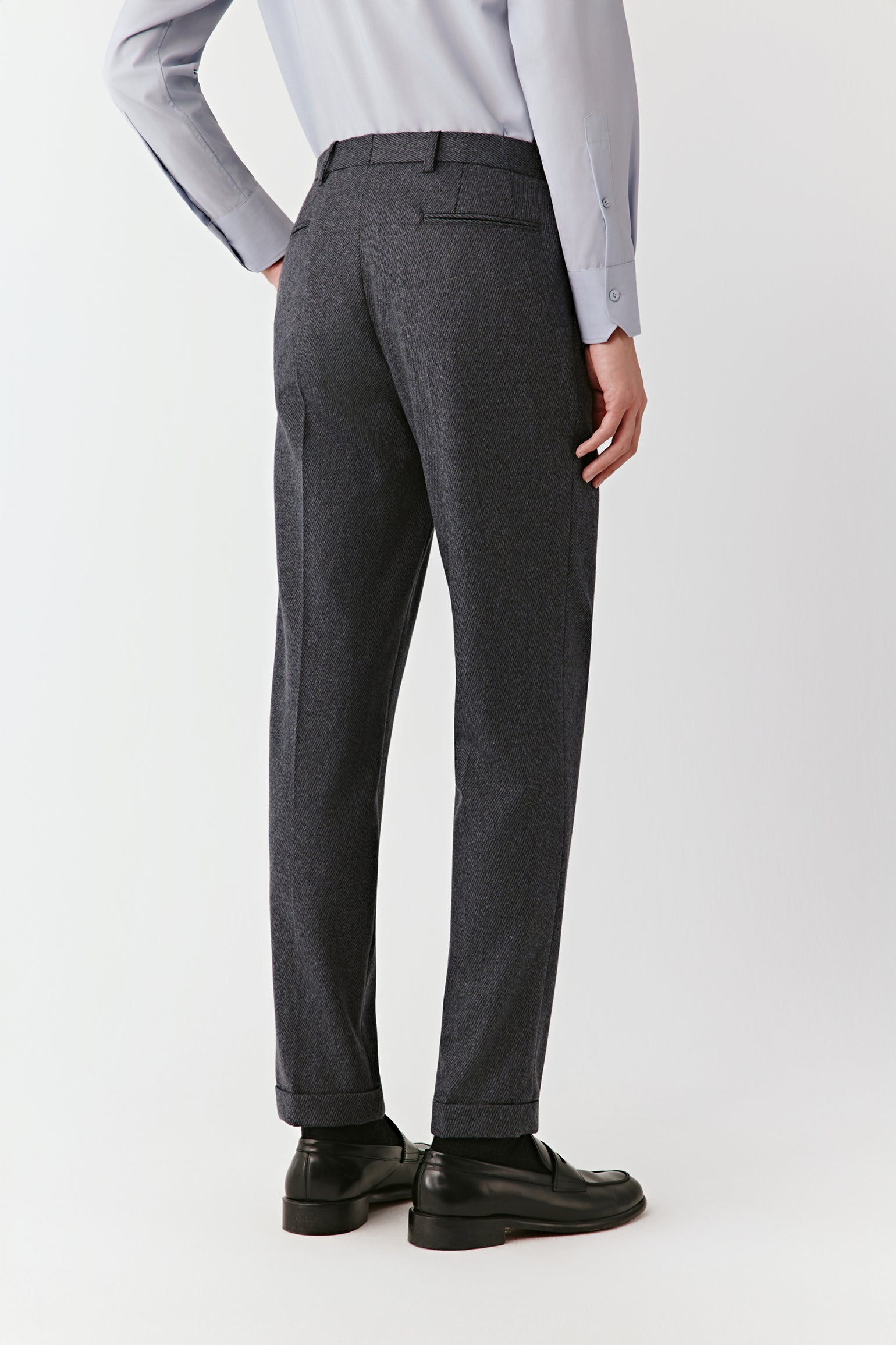 Person wearing gray dress pants and a light gray shirt on a white background