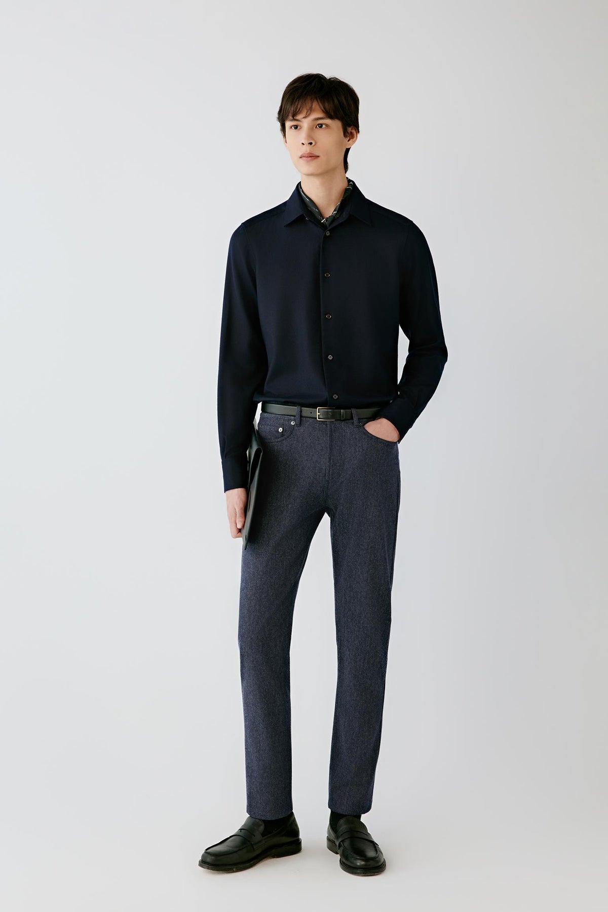 Full-length front view of a man wearing a navy wool flannel shirt with dark trousers, highlighting the pointed collar, button-front fastening and clean, relaxed silhouette.