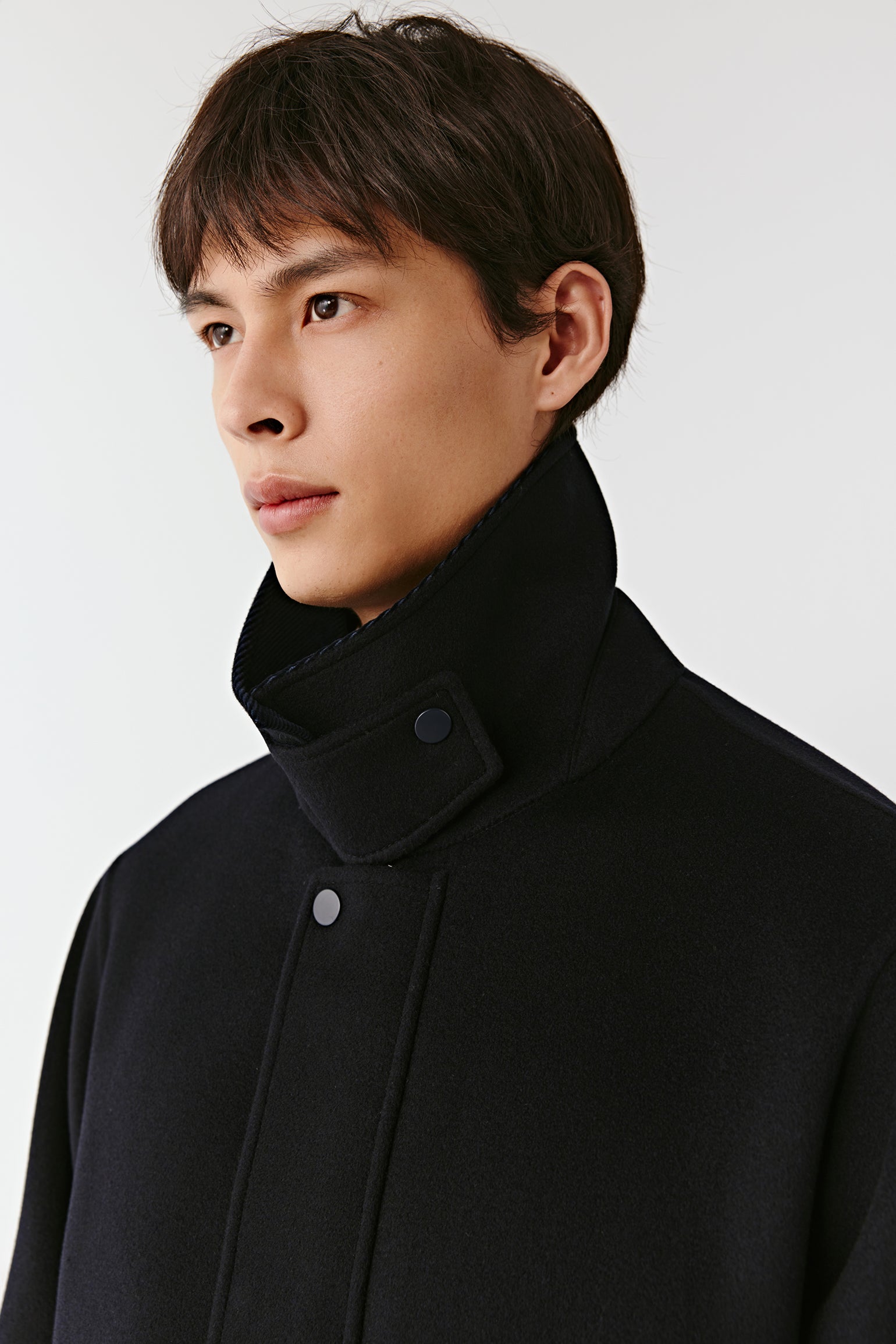 Man wearing a black coat against a white background