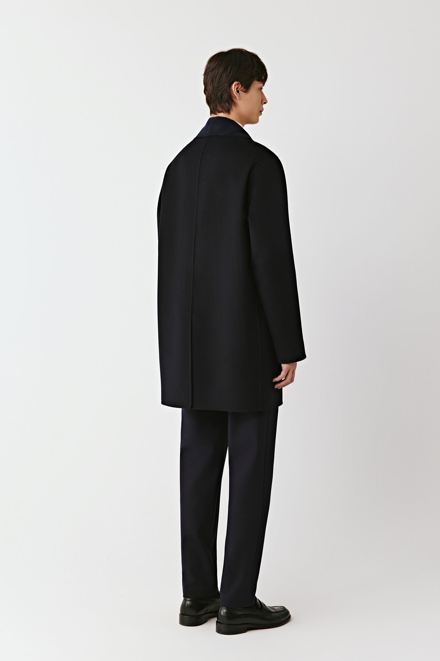 Person wearing a black coat and pants on a white background
