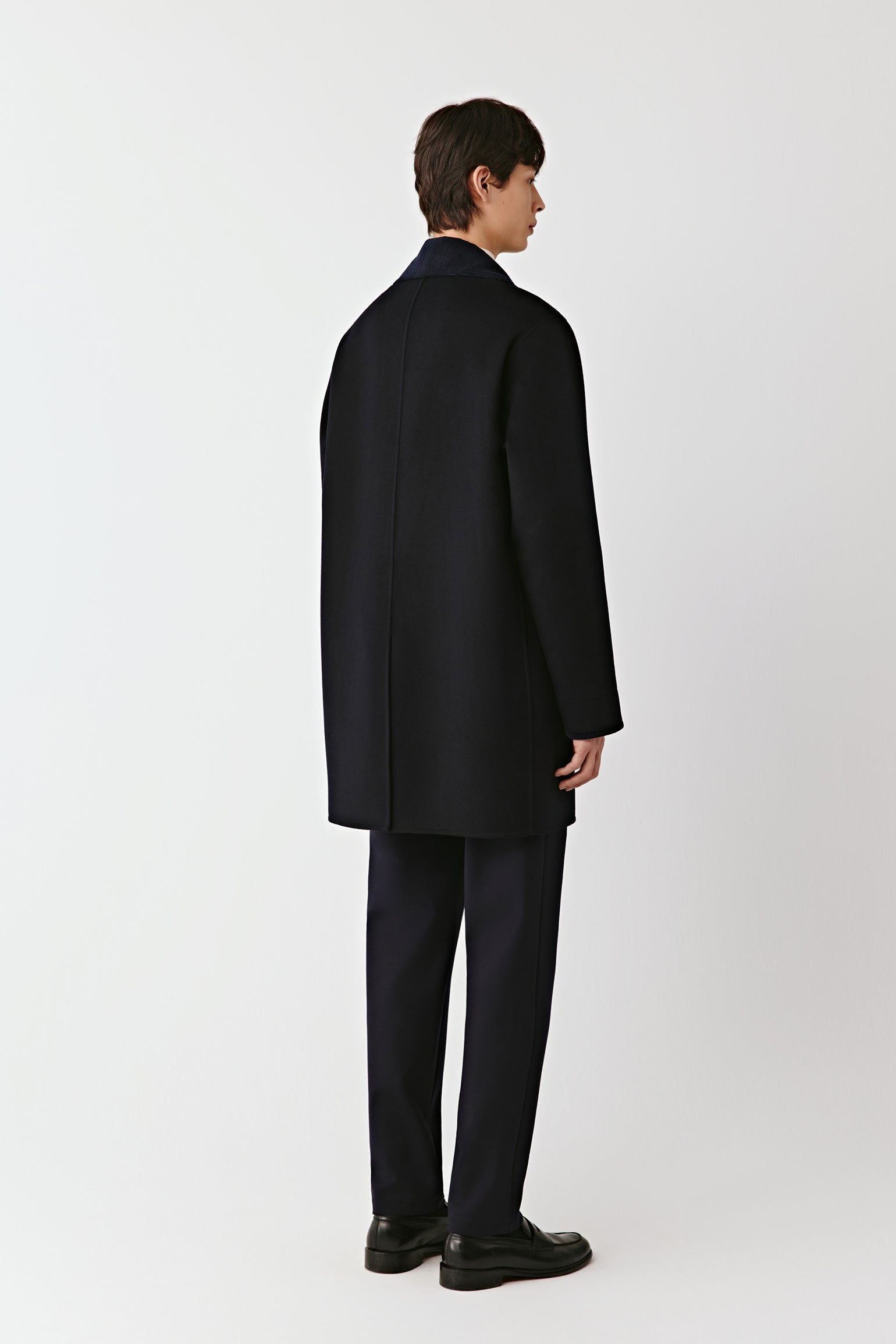 Person wearing a black coat and pants on a white background