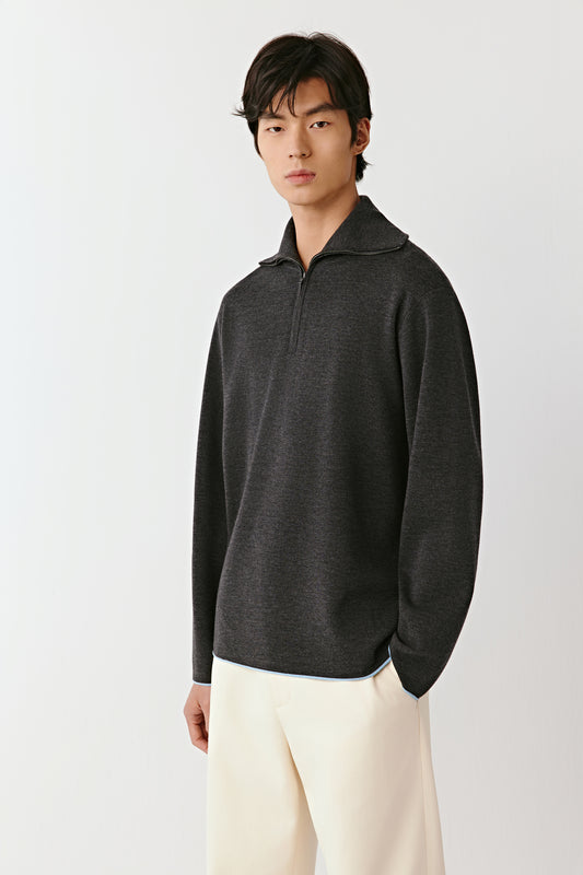 Man wearing a dark gray pullover with a high collar on a light gray background