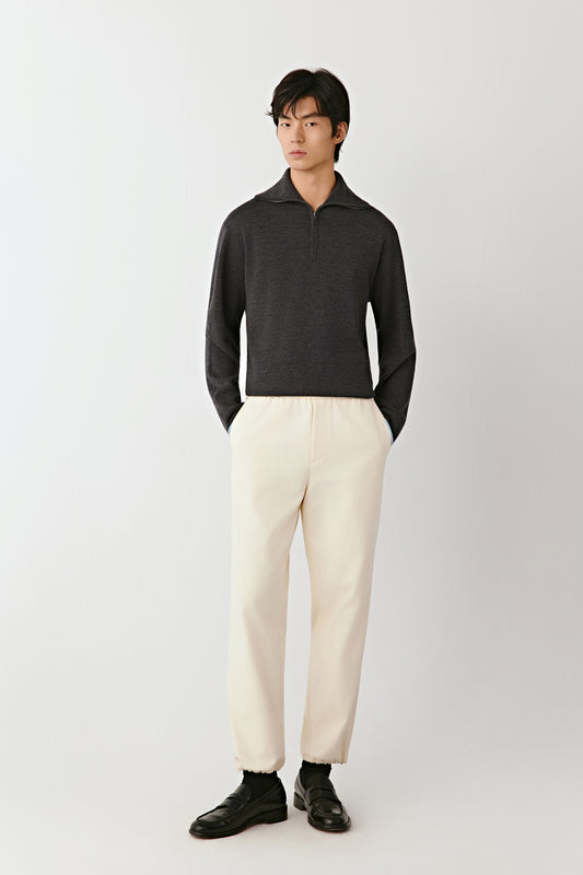 Man wearing a dark gray polo shirt and white pants on a white background