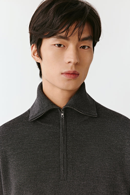 Man wearing a dark gray zip-up sweater against a white background