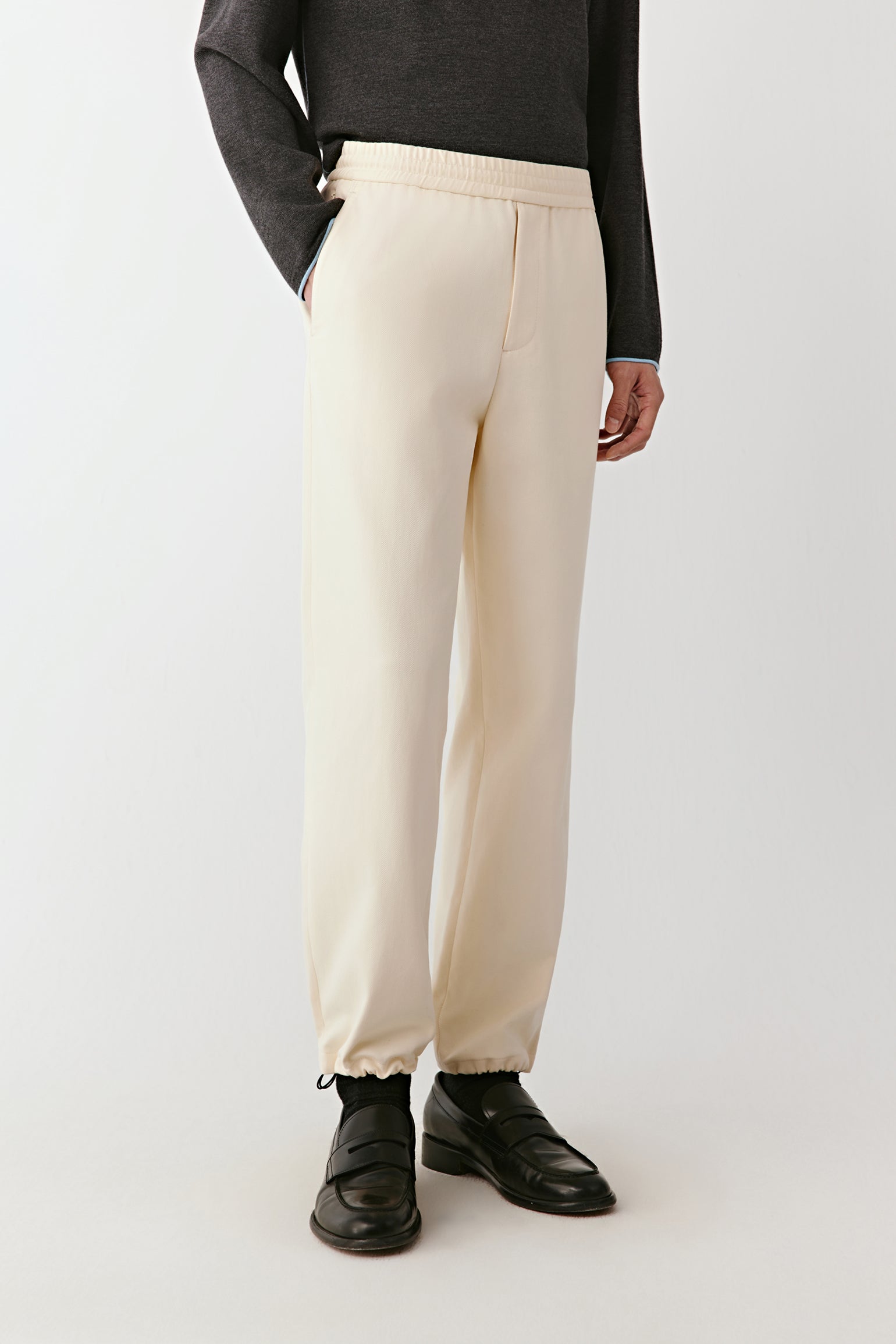 Person wearing beige pants and black shoes on a white background