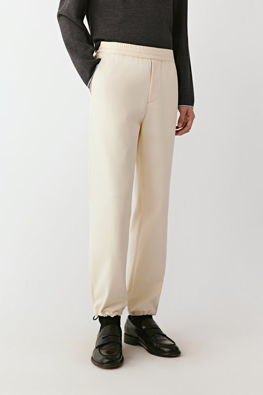 Person wearing beige pants and black shoes on a white background