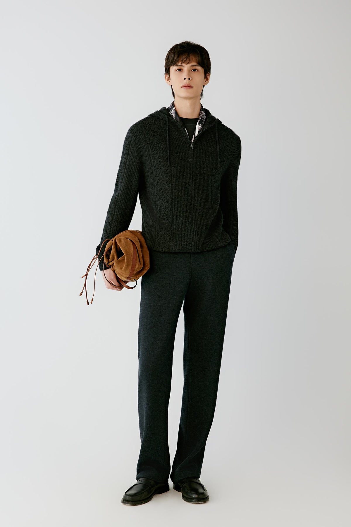 Front view of a man wearing black melange wool jersey trousers, showing the straight-leg silhouette and elasticated waistband.