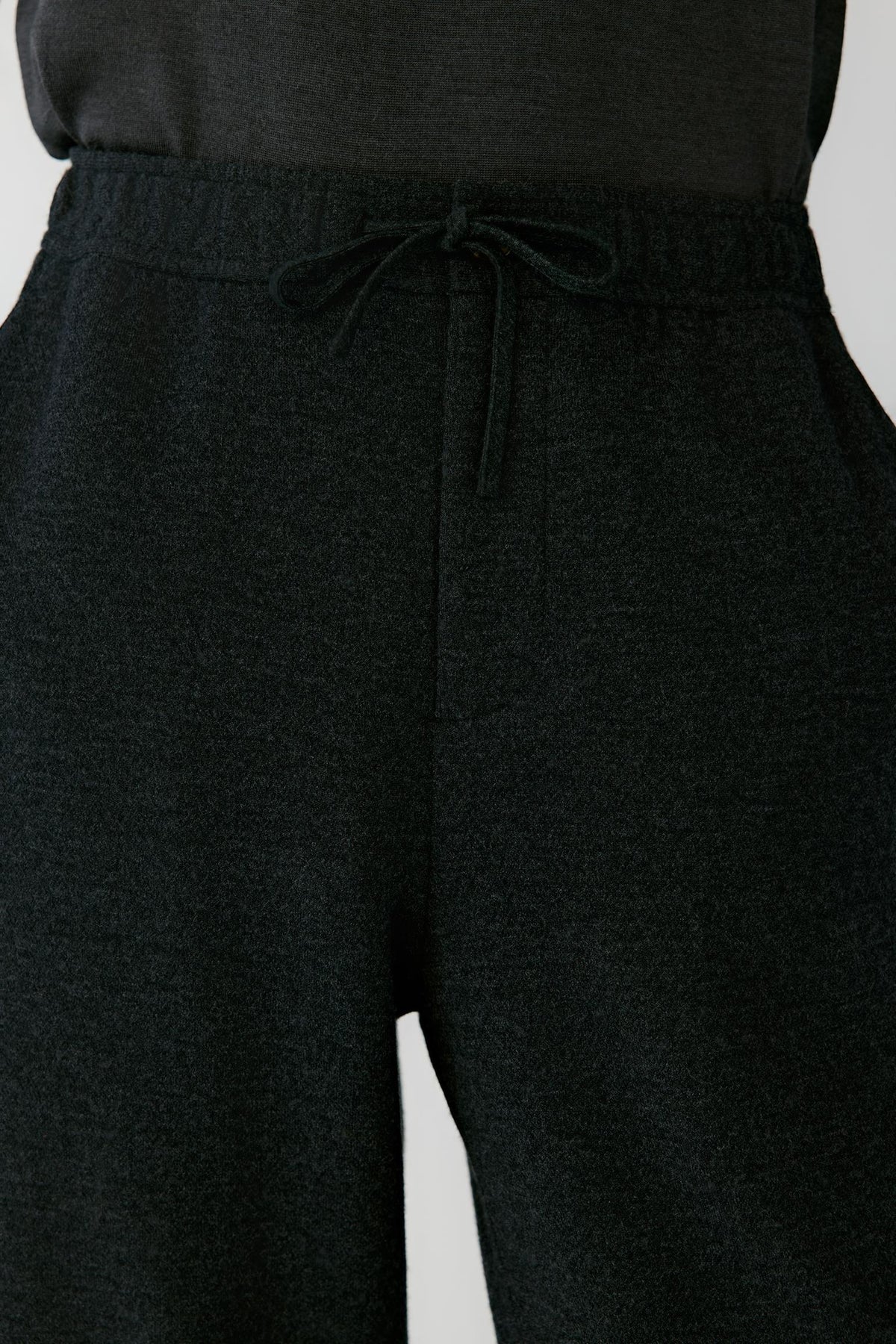 Close-up highlighting the elasticated waistband, adjustable drawstring and black melange wool jersey texture.
