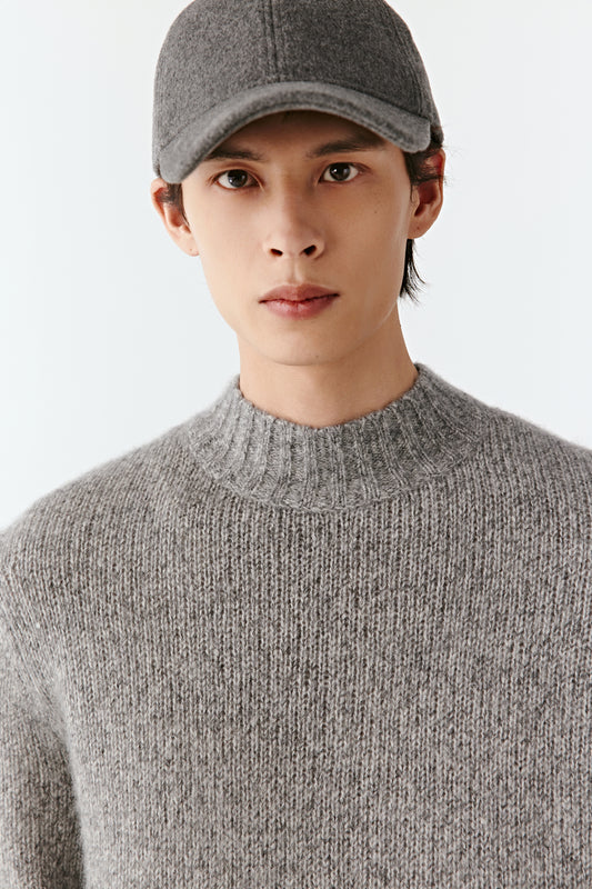 Three-quarter side view of the grey pullover, showing the fine knit texture and relaxed silhouette.
