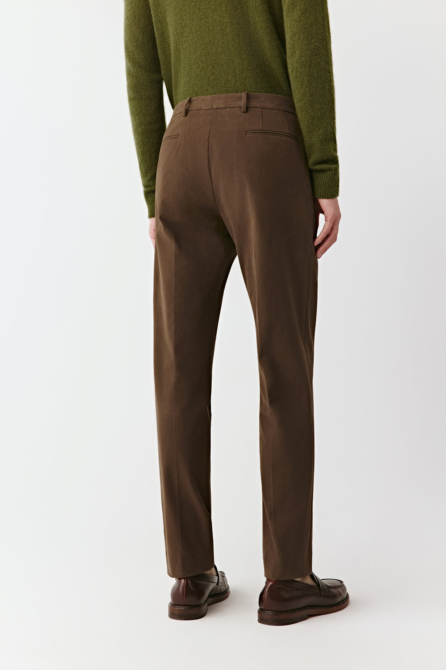 Back view of the brown trousers, highlighting the welt pockets and clean lines.
