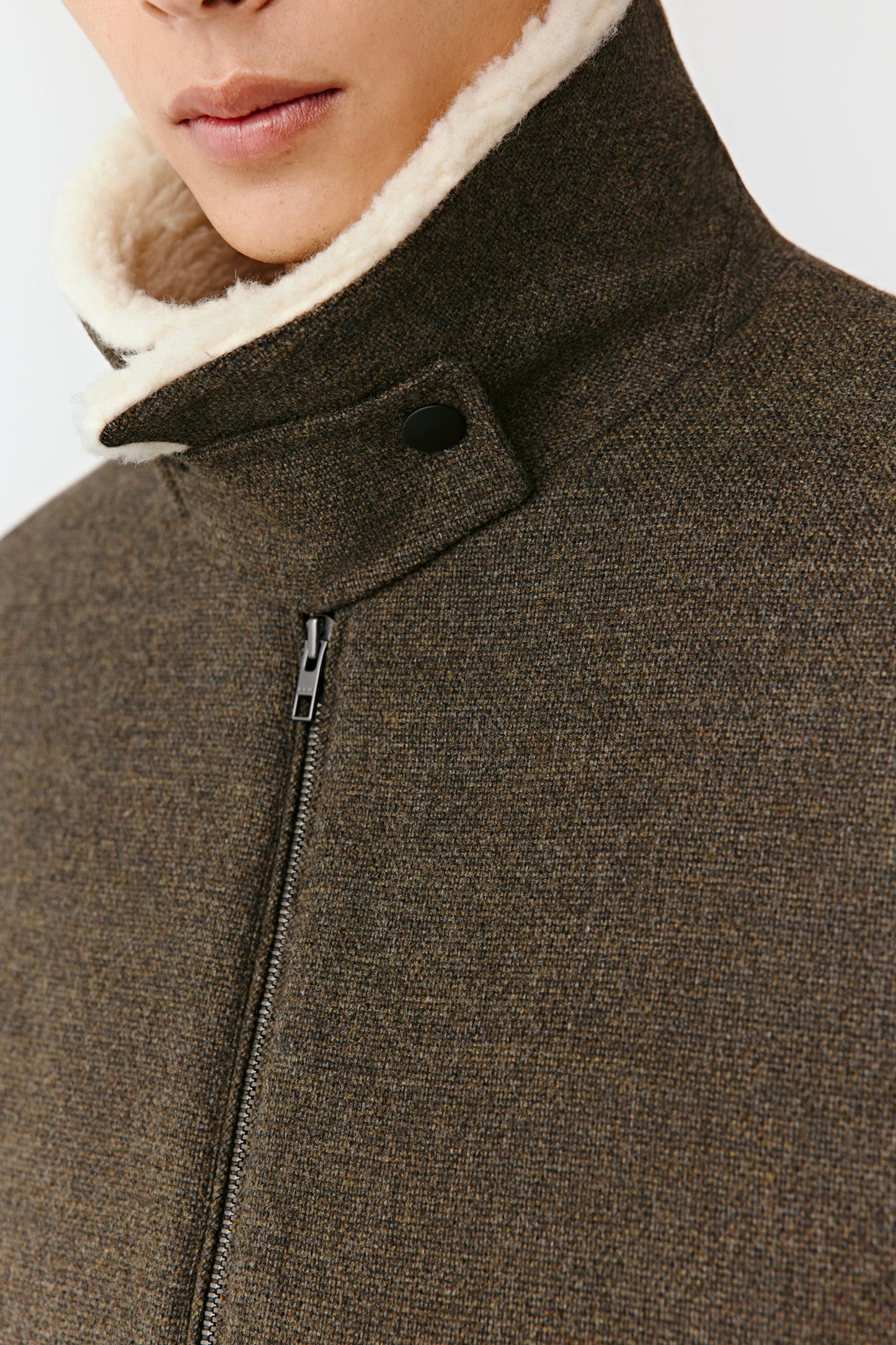 Close-up of the khaki green jacket’s collar and concealed zip, showing the fine texture and trimmed edges.