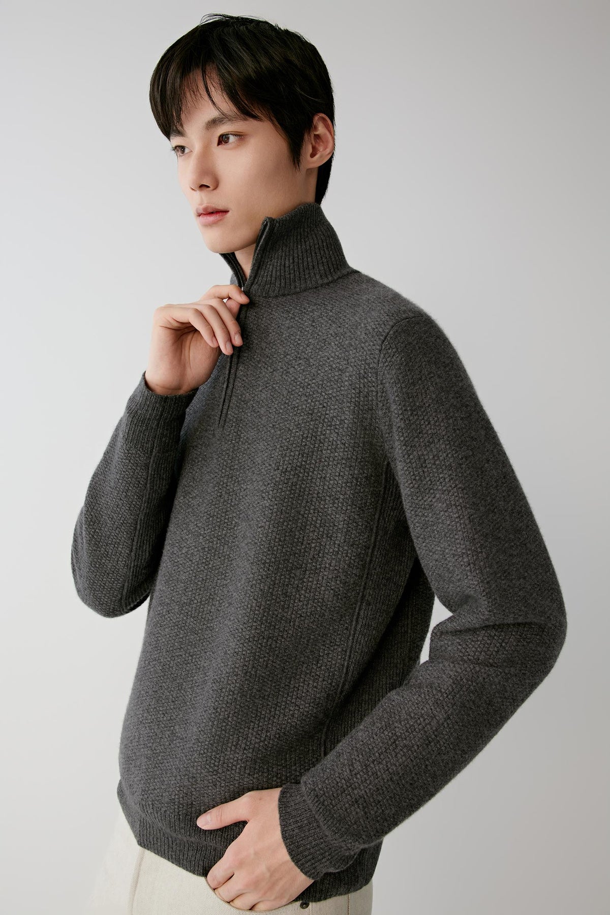 Three-quarter view of a man wearing the smoke grey cashmere pullover, showing the high collar, long sleeves and straight silhouette.