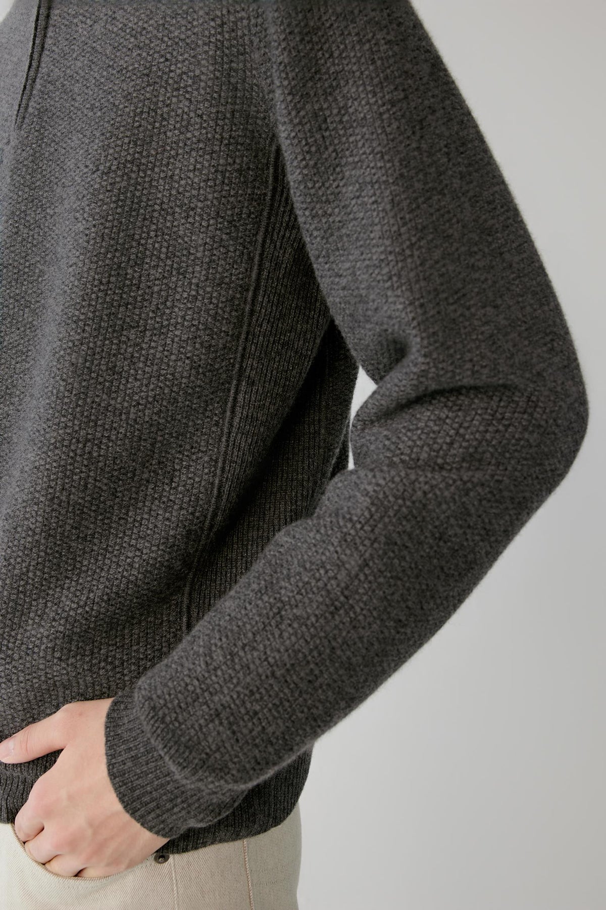 Close-up highlighting the long sleeve, ribbed cuff and textured smoke grey cashmere knit.