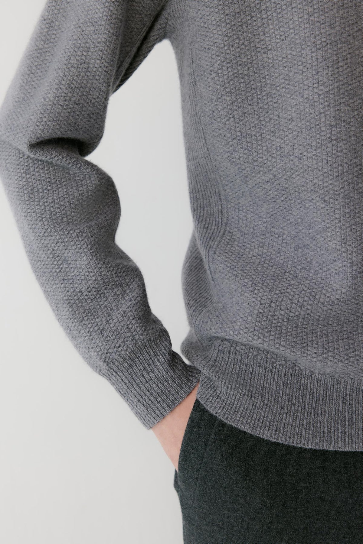 Close-up highlighting the long sleeve, ribbed cuff and textured grey cashmere knit.