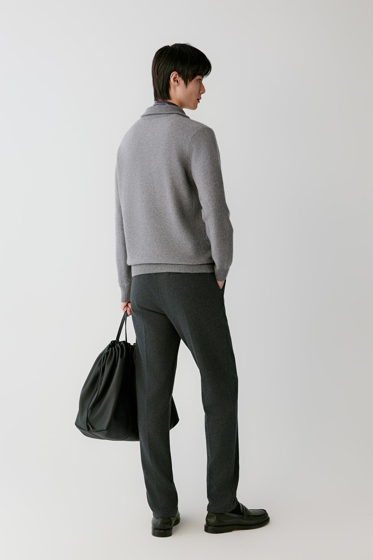 Three-quarter view of a man wearing the grey cashmere pullover, showing the straight silhouette and long sleeves.