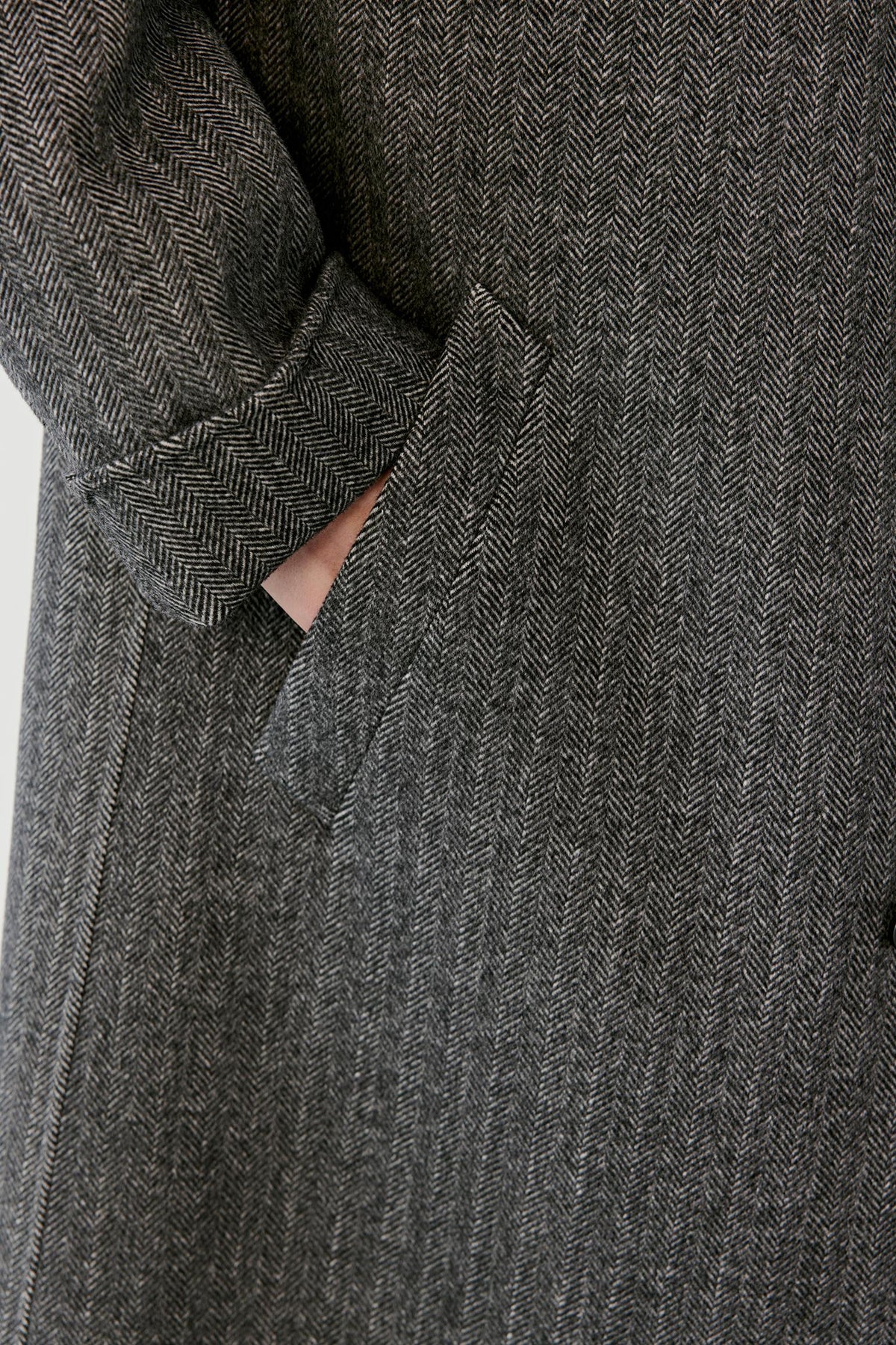 Close-up highlighting the black and white herringbone pattern and textured wool and cashmere surface.