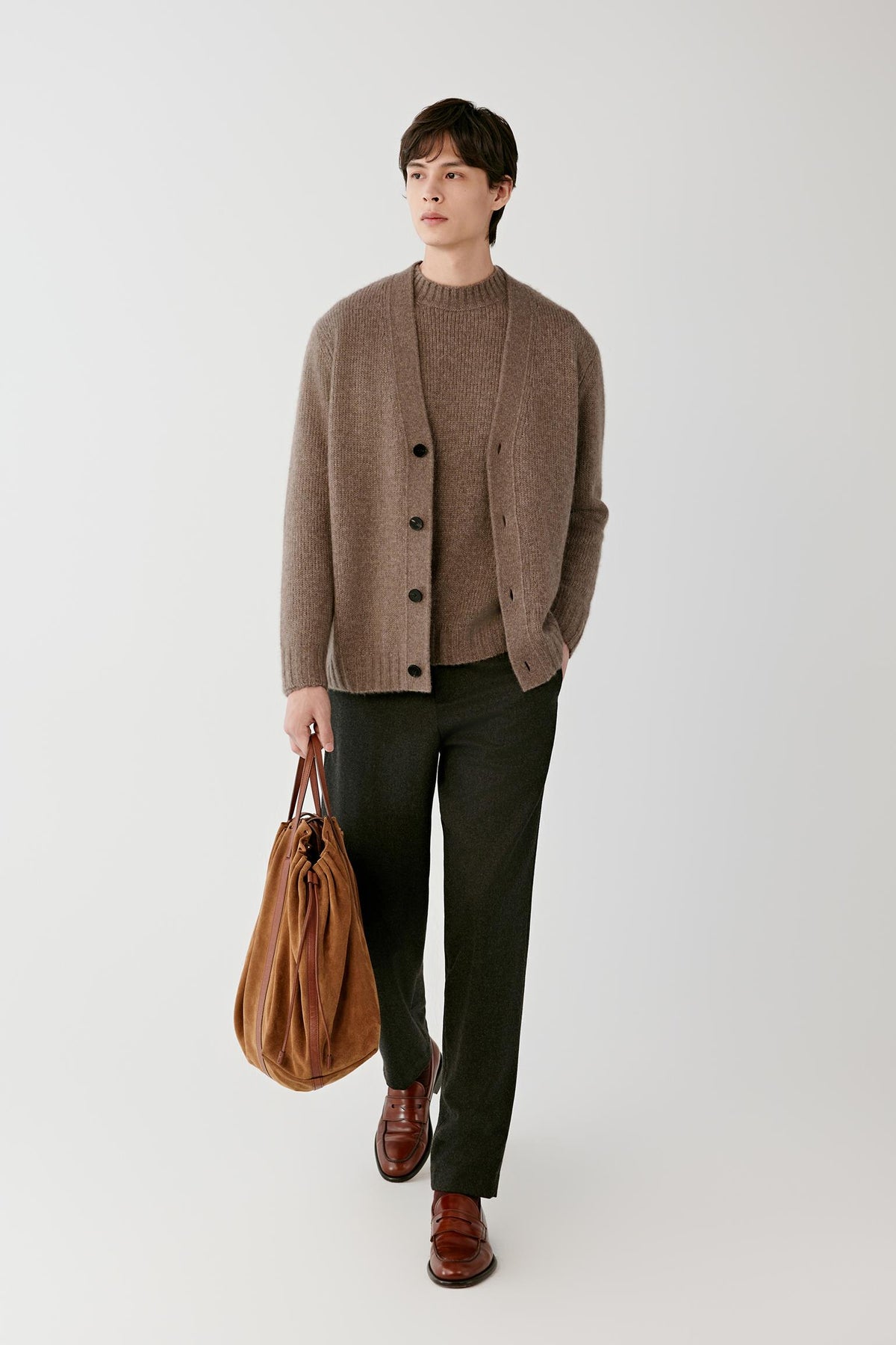 Front view of a man wearing a warm brown cashmere pullover, showing the round neckline, button-front detail and straight silhouette.