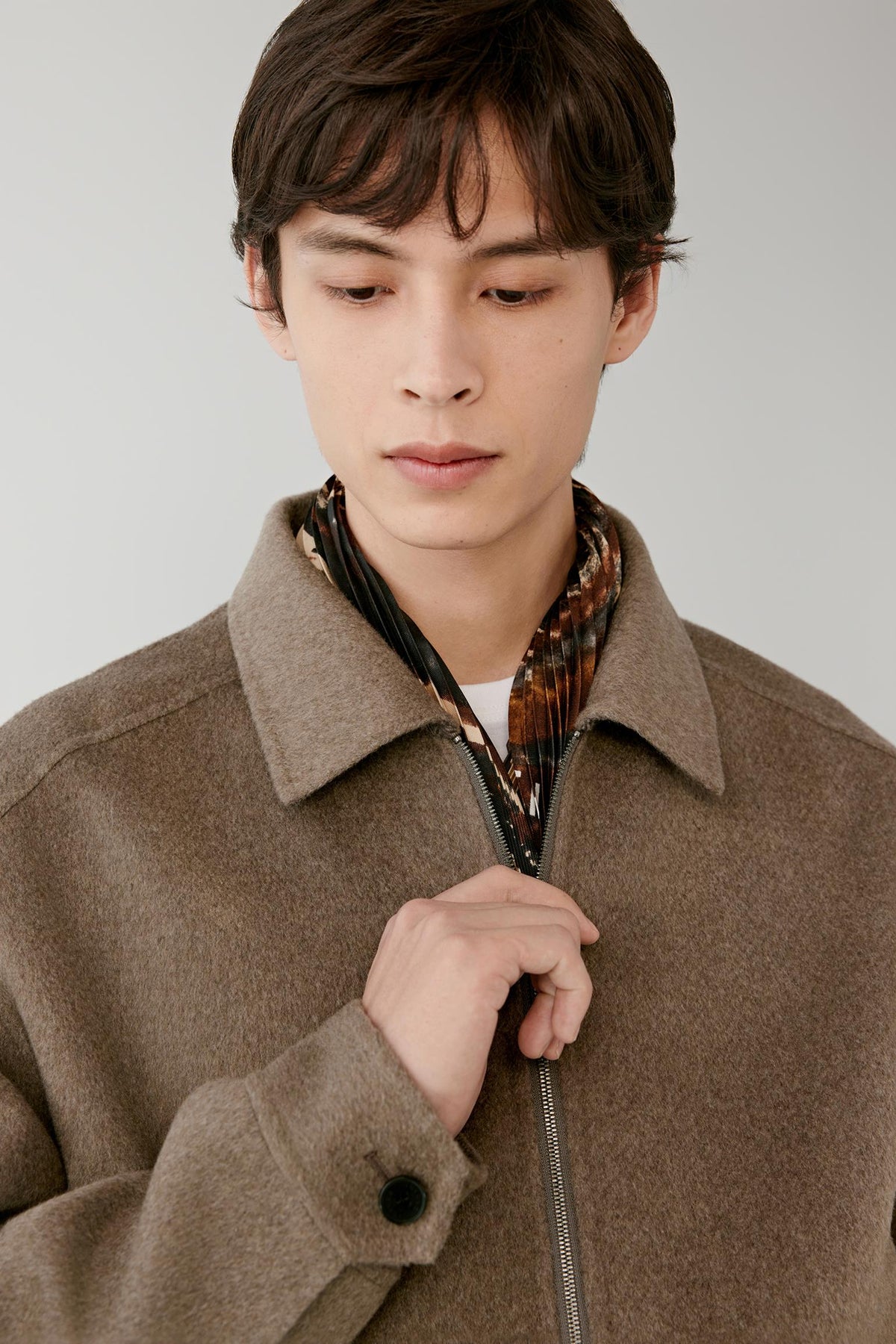 Close-up highlighting the pointed collar, front zip fastening and brown melange cashmere texture.