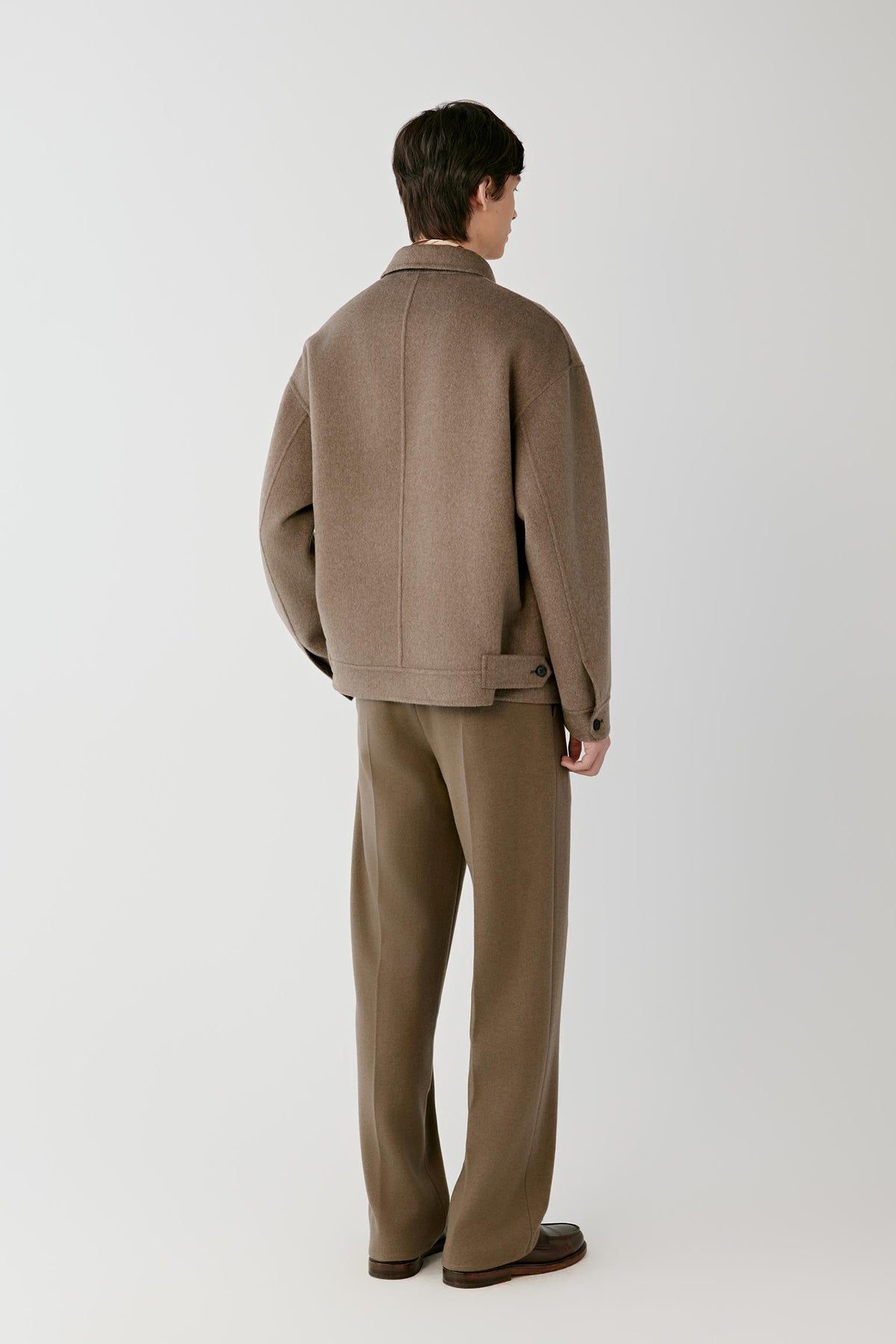 Back view of a man wearing the brown melange cashmere jacket, showing the clean back and straight silhouette.