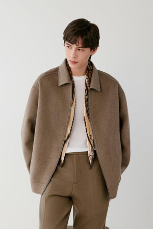 Front view of a man wearing a brown melange cashmere jacket, showing the relaxed silhouette, pointed collar and front zip fastening.