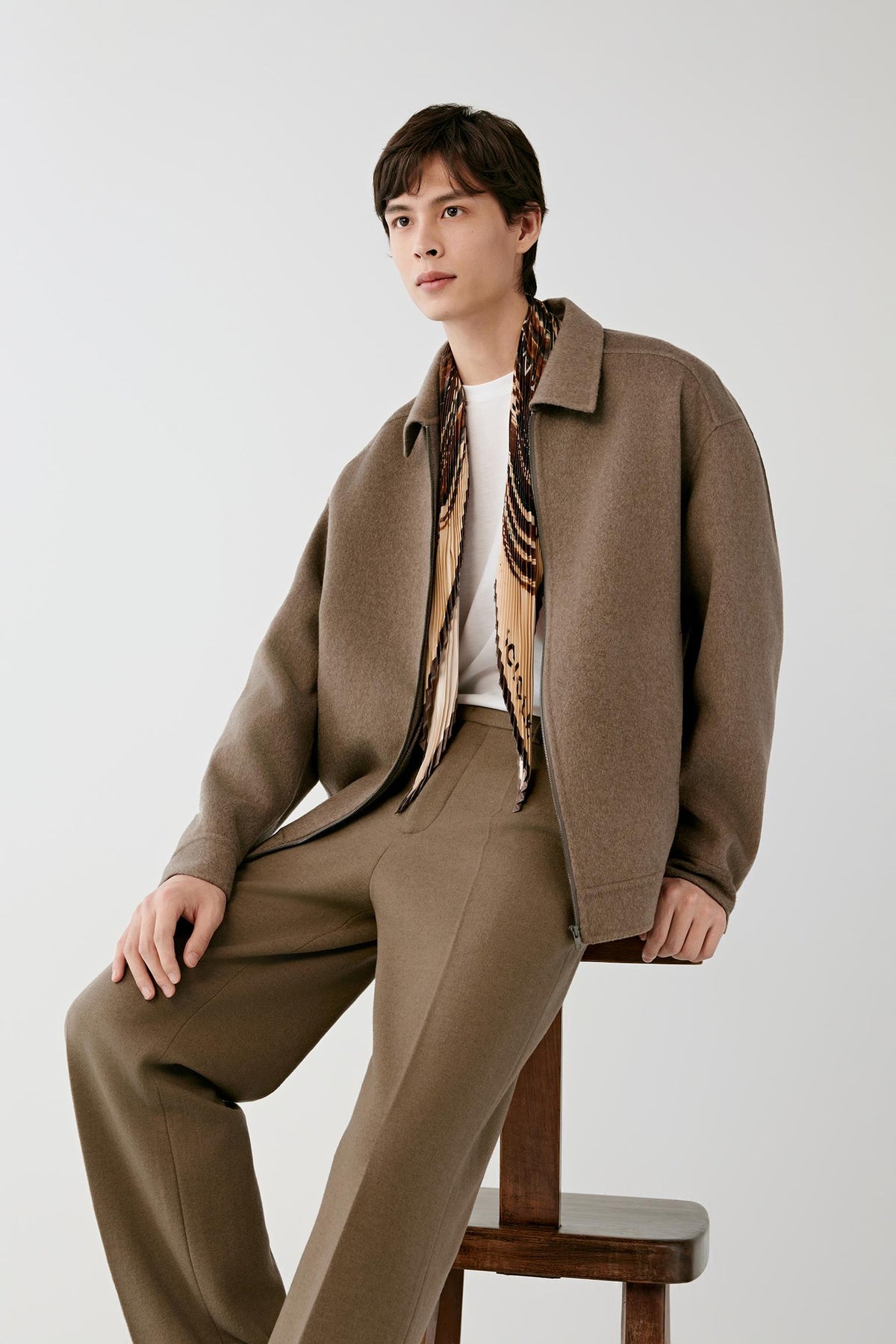 Three-quarter view of a man wearing the brown melange cashmere jacket, highlighting the relaxed shape and brown melange surface.