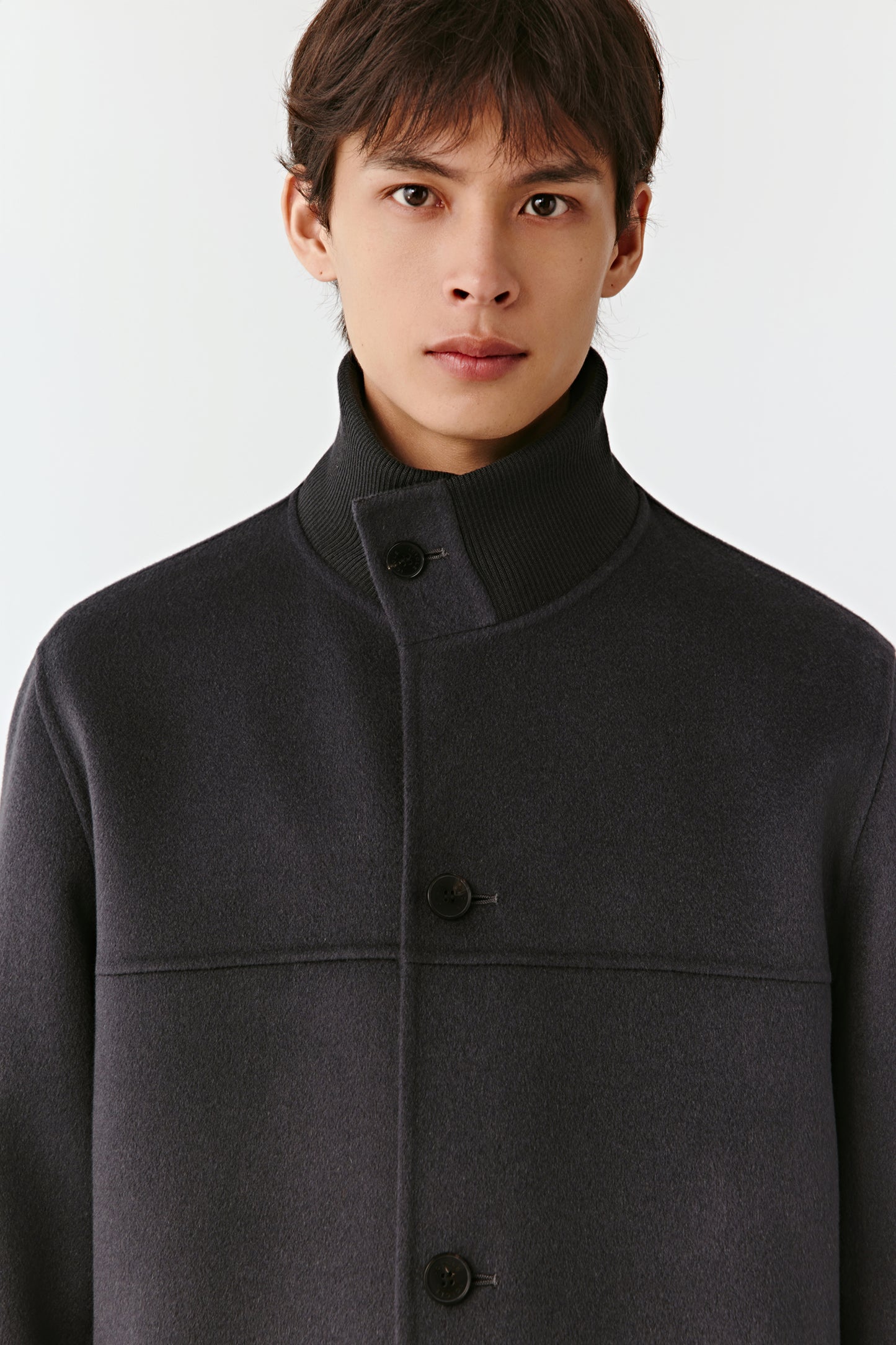 Man wearing a dark gray coat against a white background