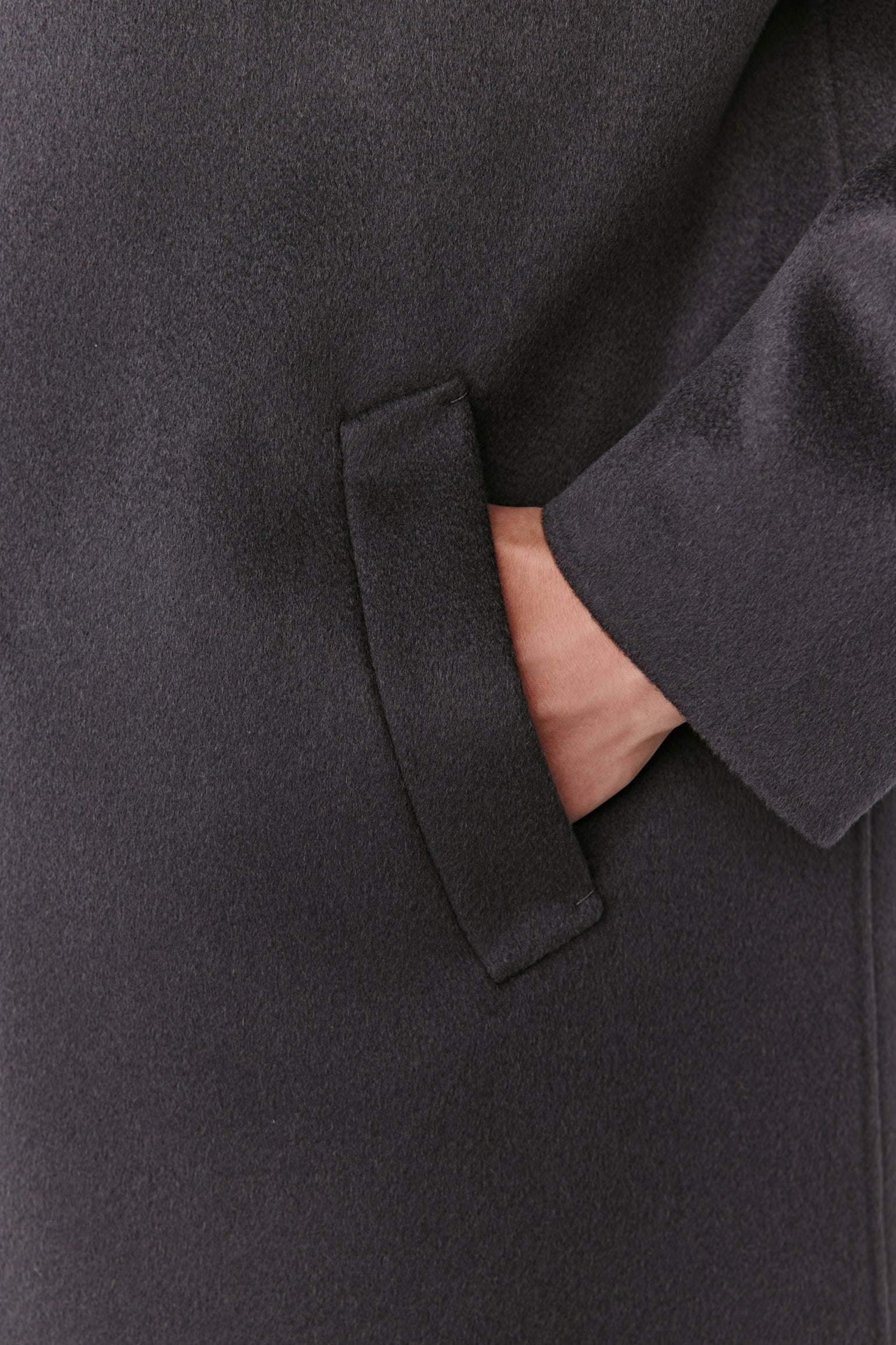 Close-up of a dark gray coat with a hand in the pocket