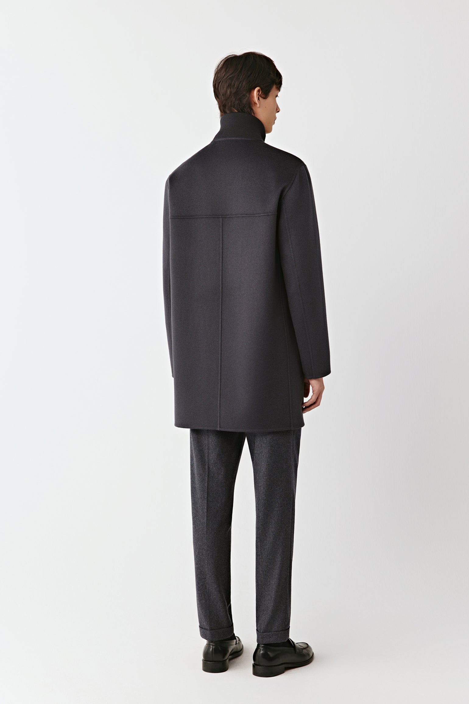 Man wearing a dark gray coat and pants on a white background