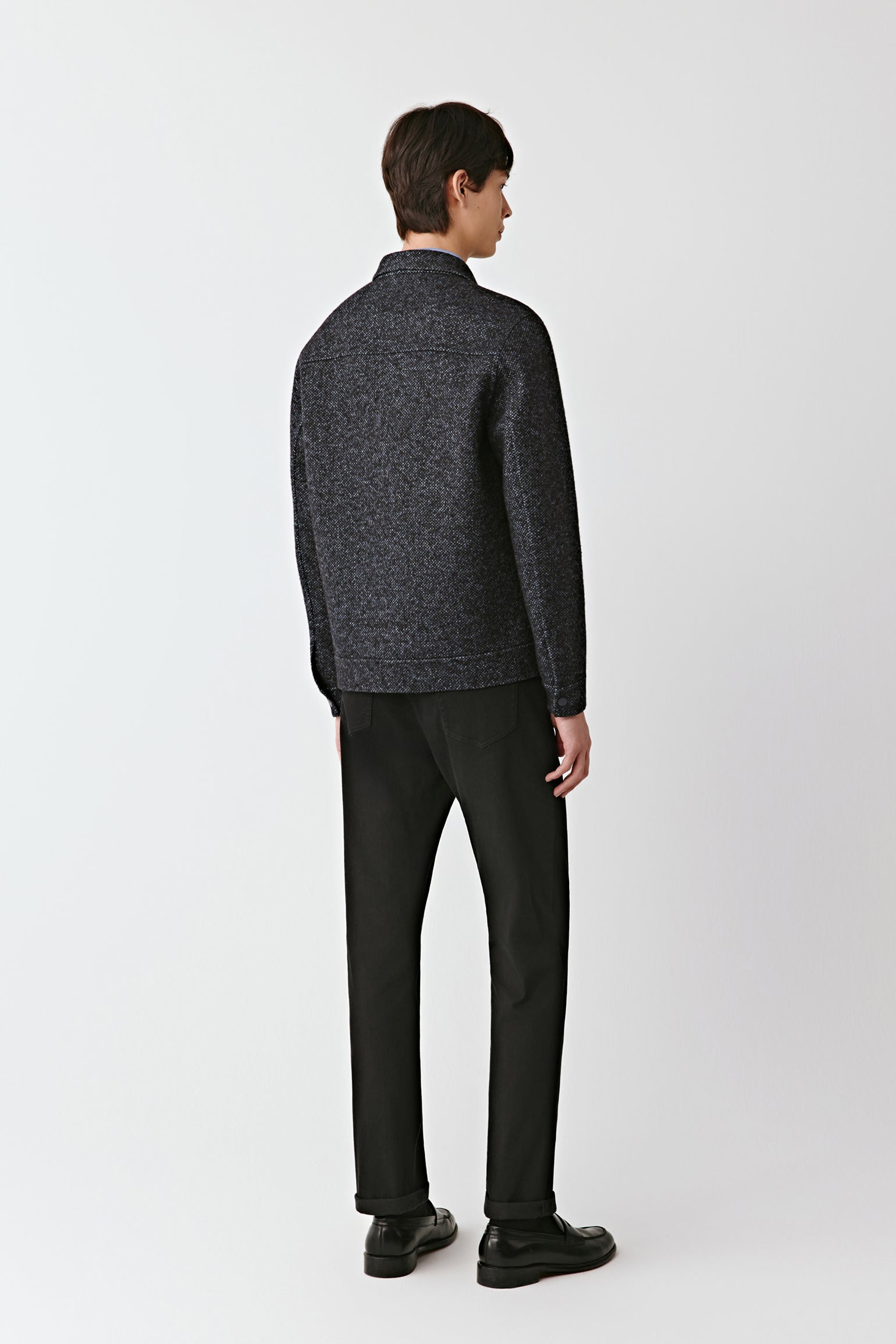 Man wearing a dark gray sweater and black pants on a white background