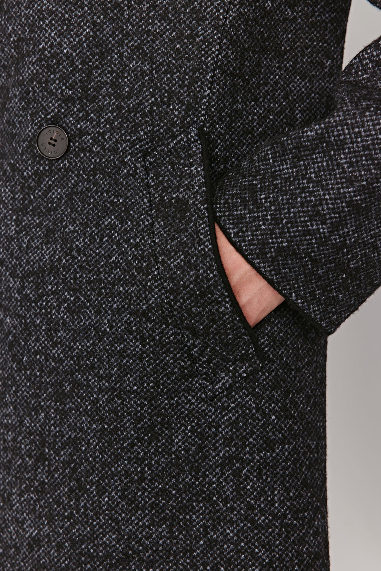 Close-up of a dark gray textured coat with a button on a white background