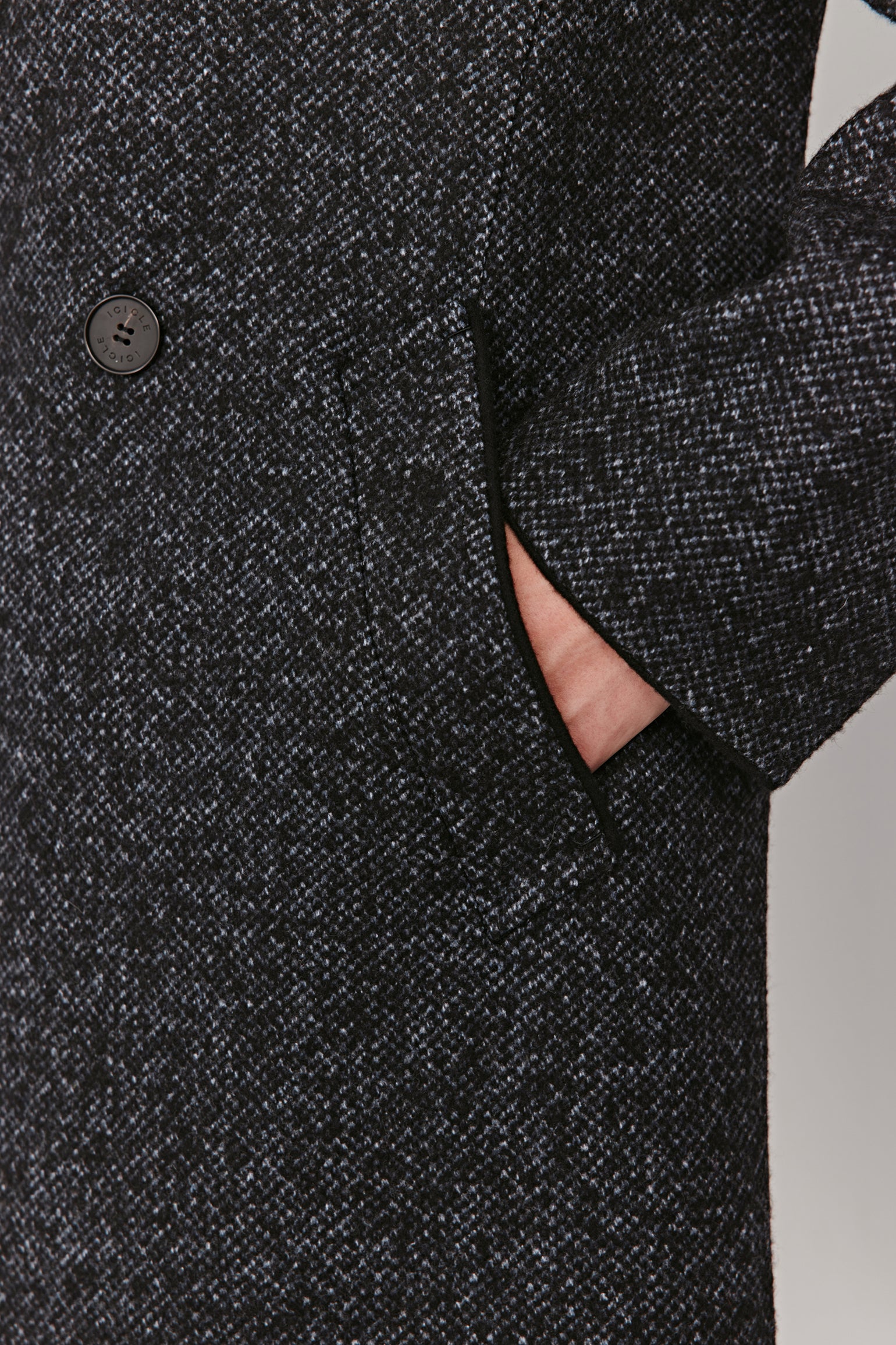 Close-up of a dark gray textured coat with a button on a white background