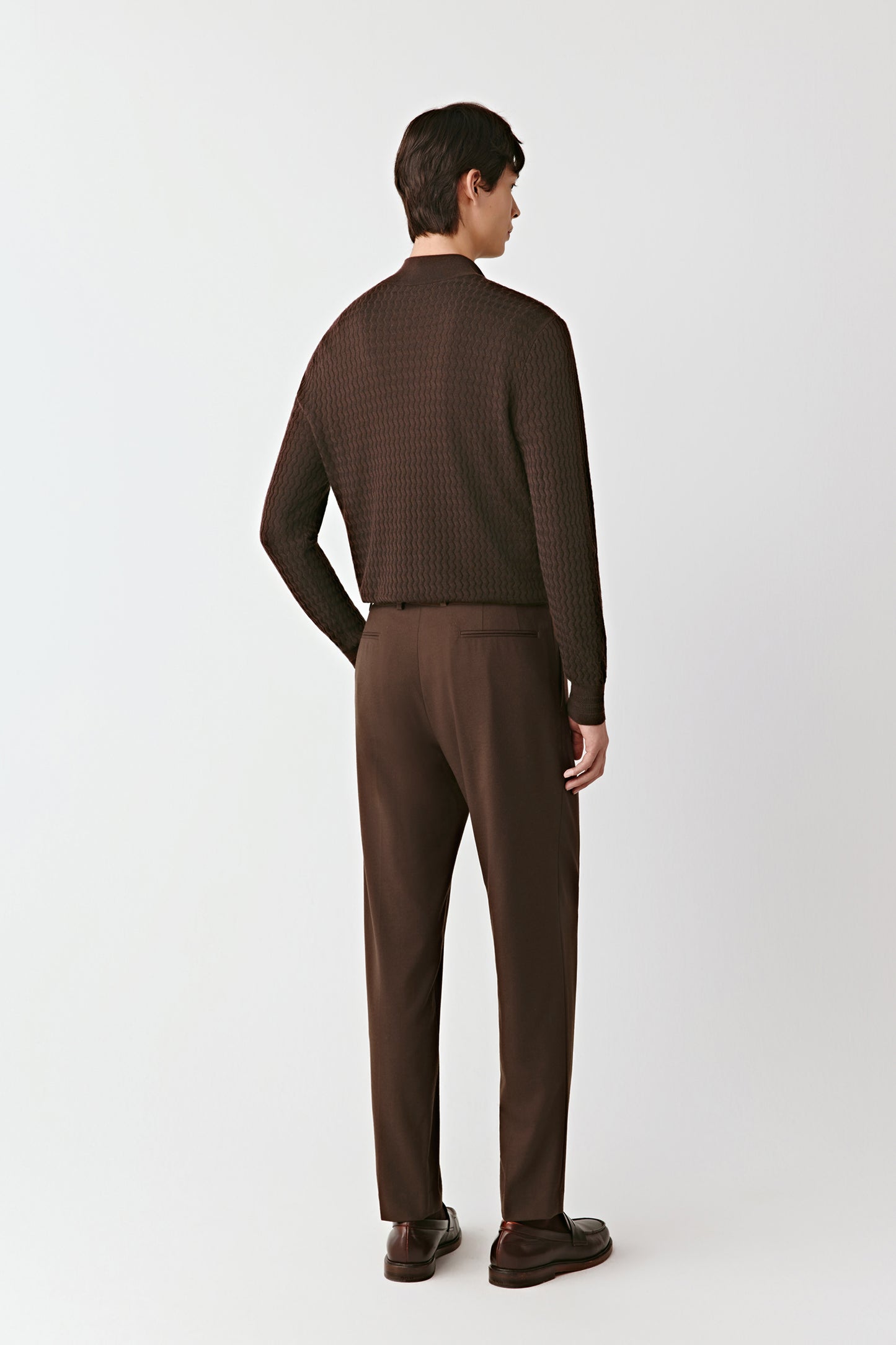 Man wearing a brown checkered sweater and pants on a white background