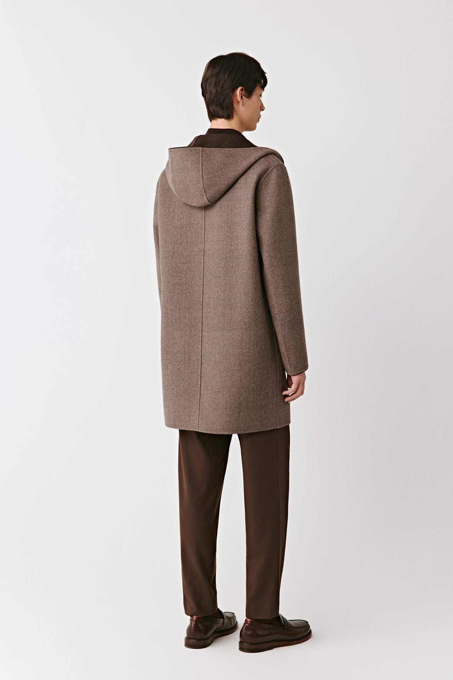 Person wearing a brown coat on a white background