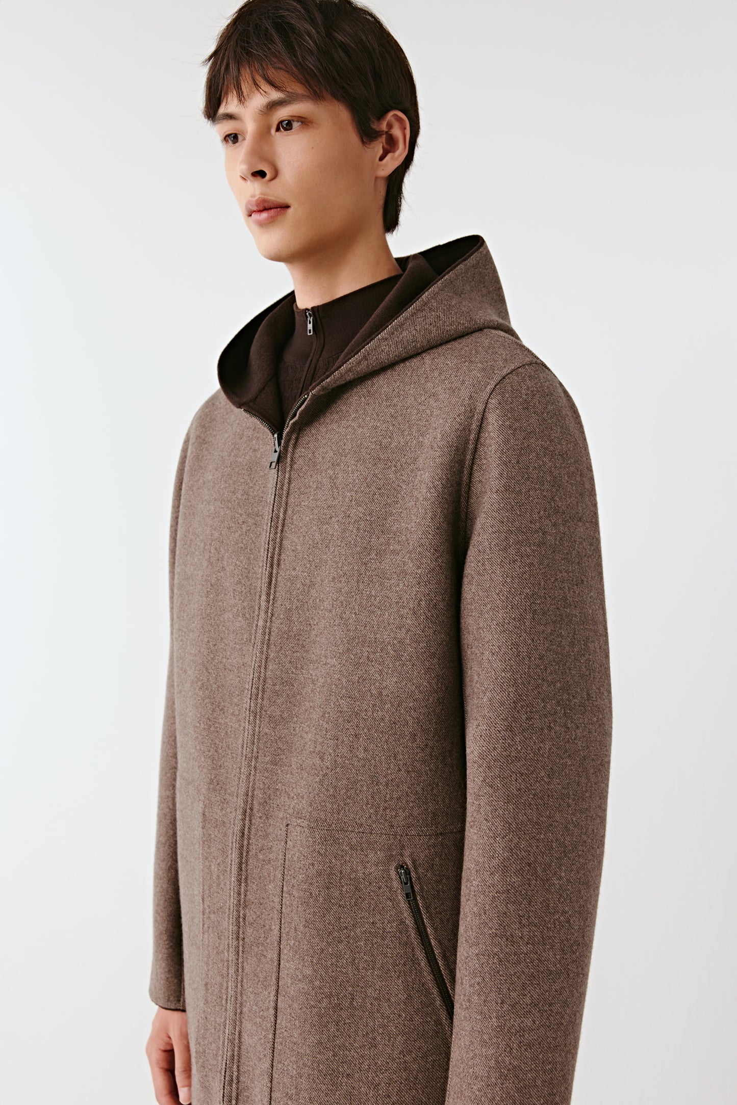 Man wearing a brown hooded coat on a white background