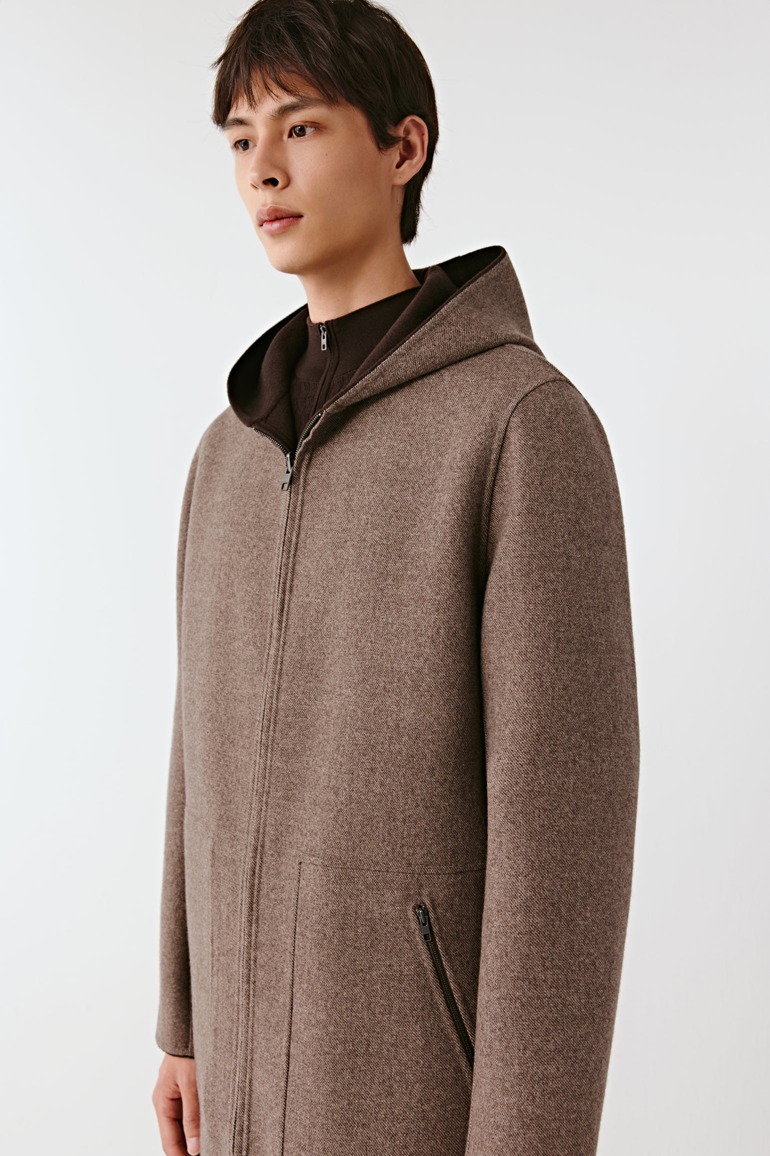 Man wearing a brown hooded coat on a white background