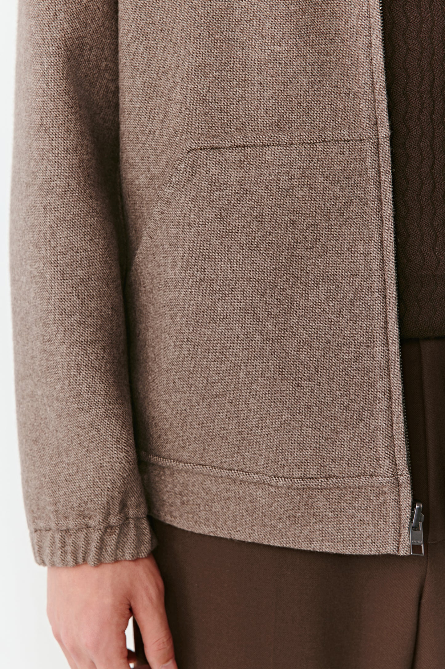 Close-up of a brown textured jacket with a zipper on a white background
