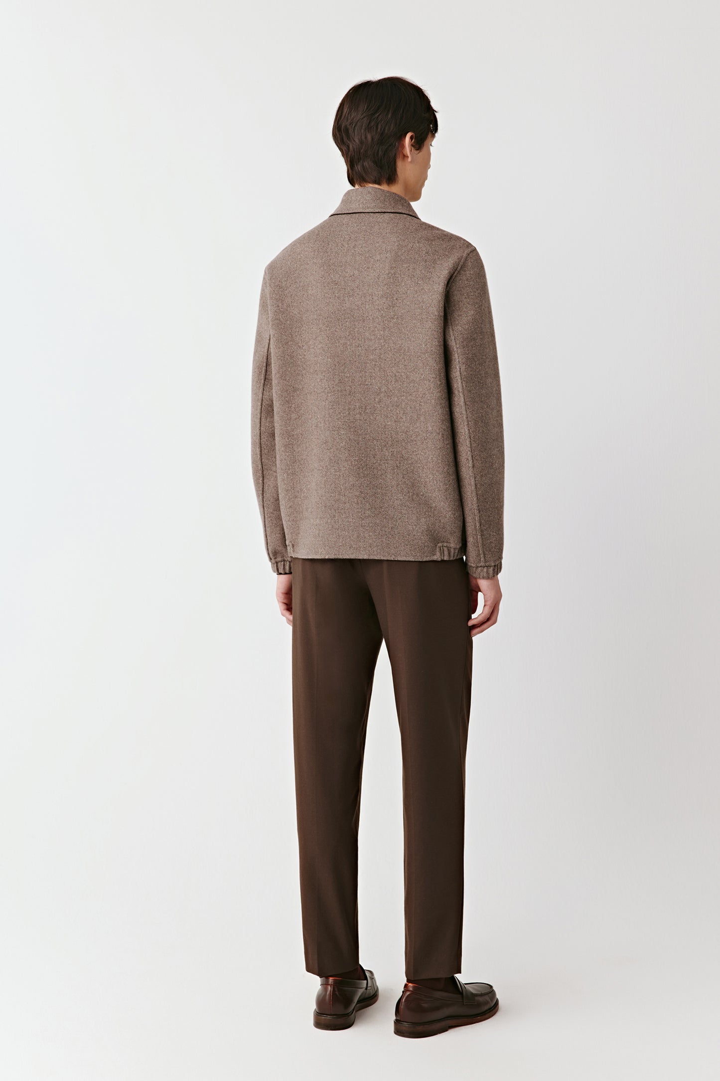 Man wearing a brown checkered jacket and brown pants on a white background