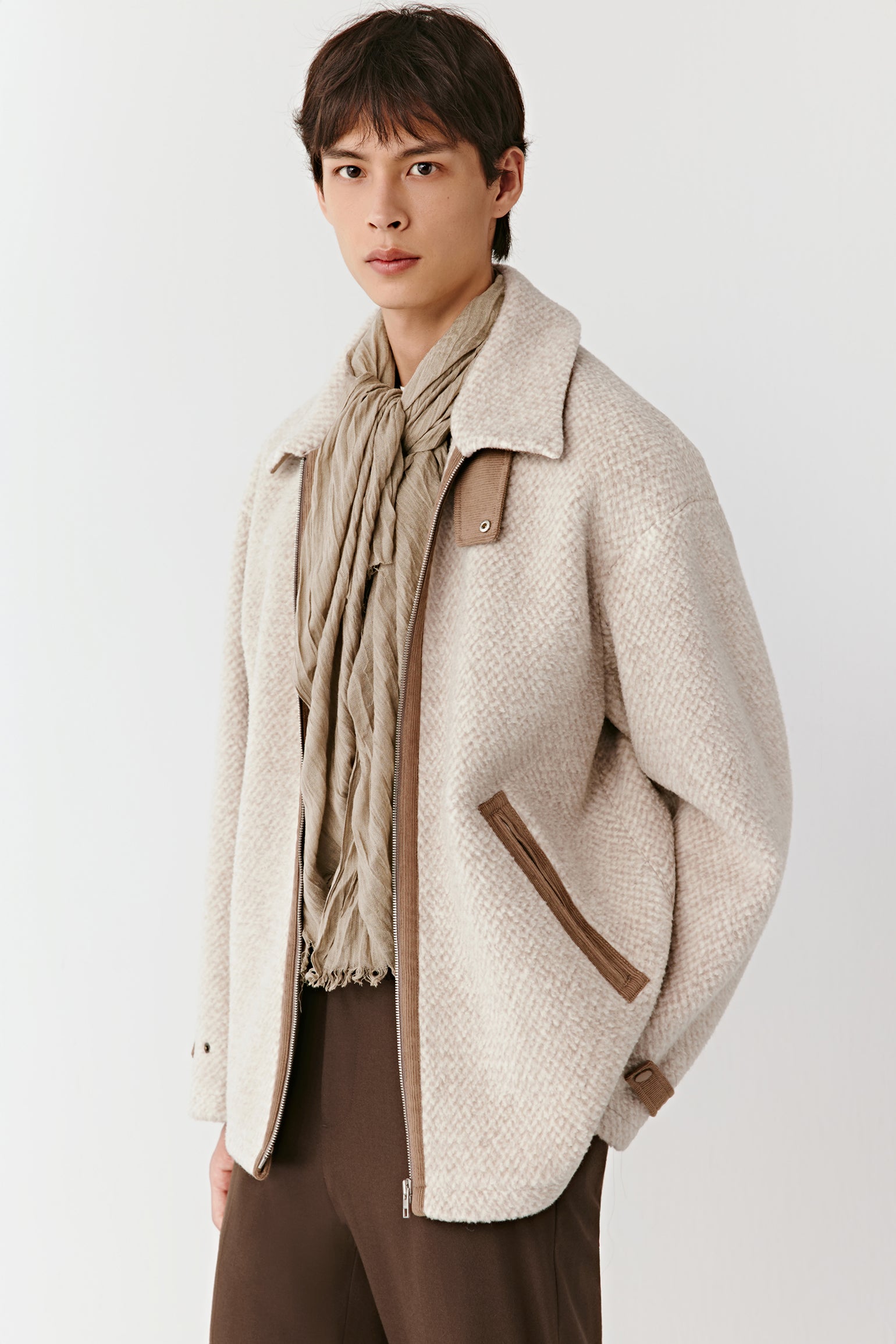 Man wearing a beige textured jacket with brown accents on a white background