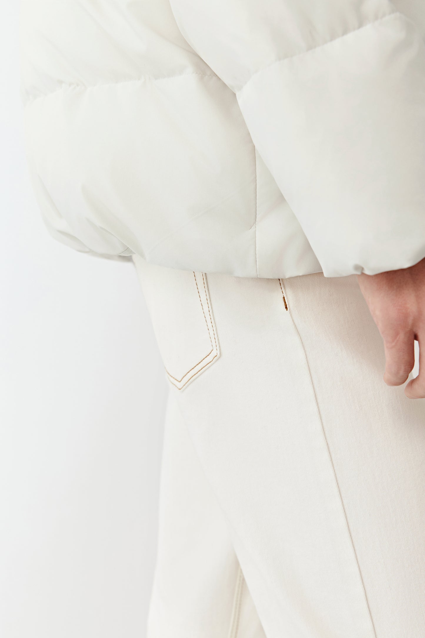 Detail close-up of the side pocket and quilted texture of the recycled polyester puffer coat.